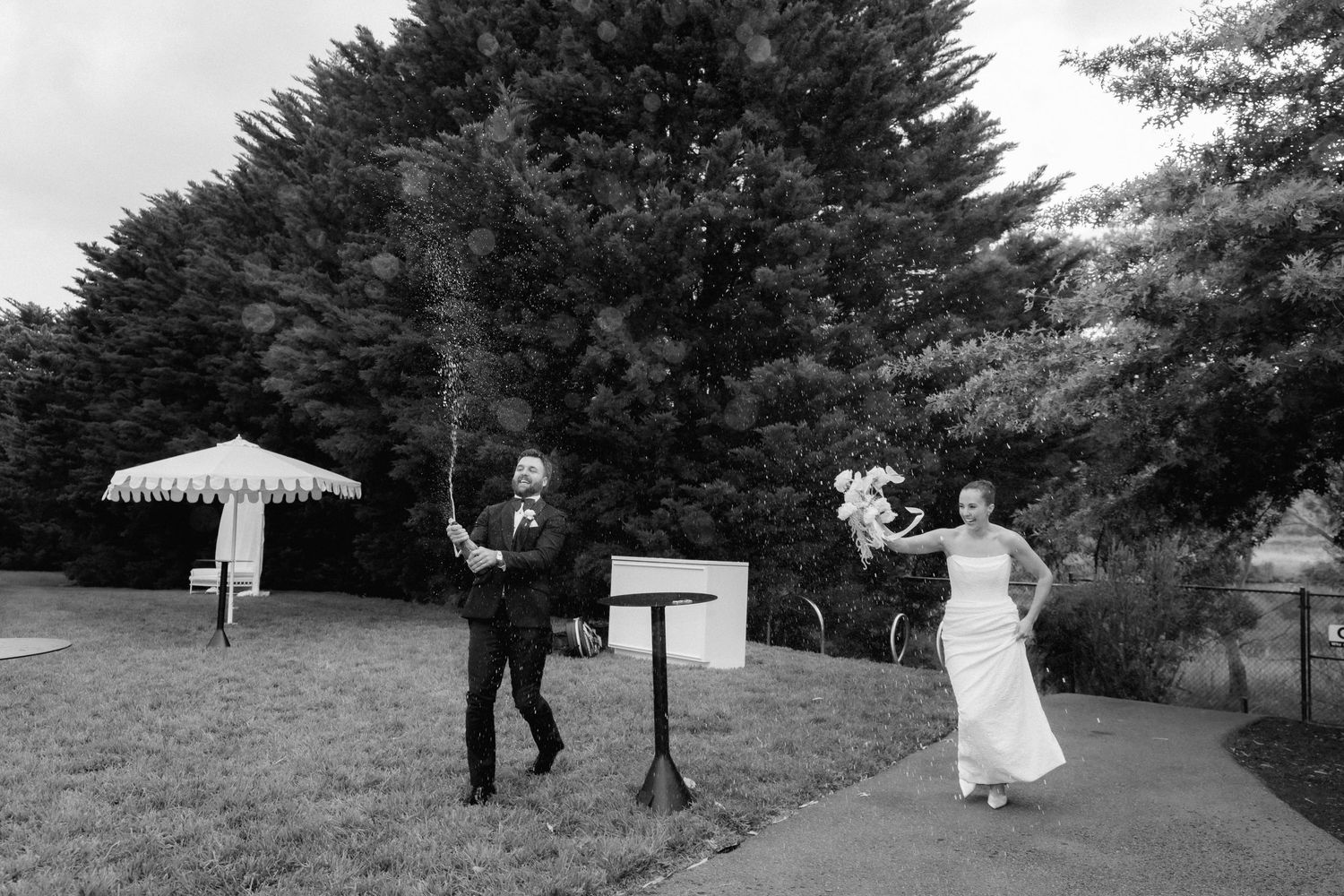 Black and white photo of bride and groom with officiant during outdoor wedding ceremony.