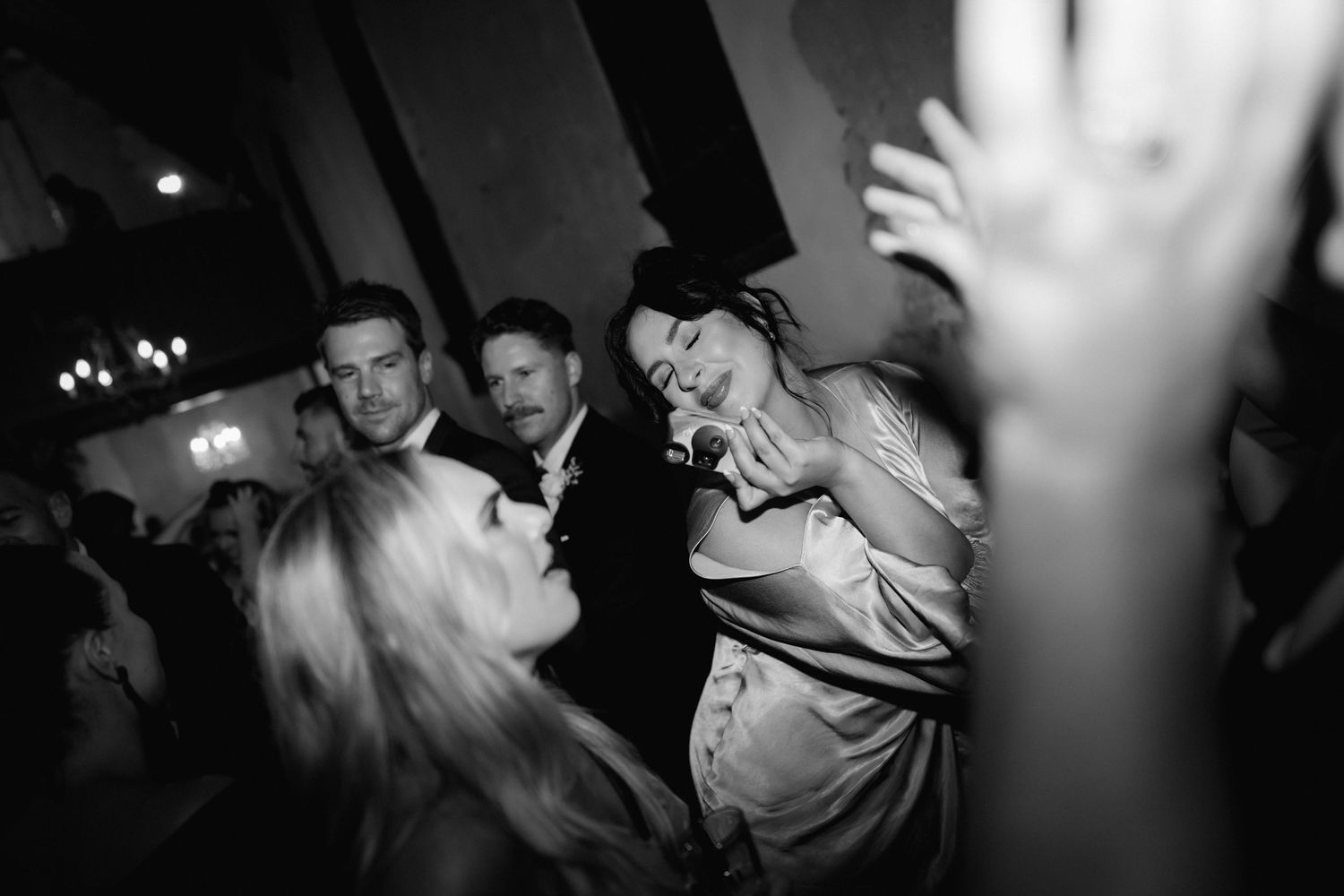 Black and white photo of people dancing and celebrating energetically at a party or nightclub event.