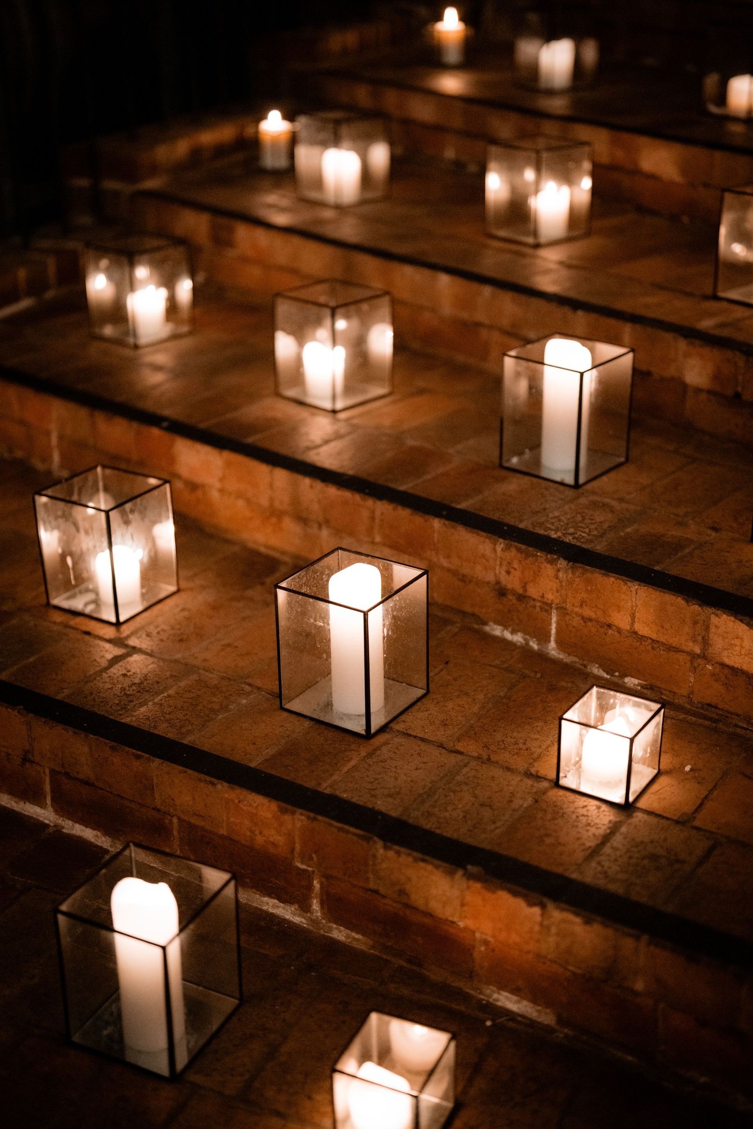 Glass lanterns with glowing candles arranged on rustic wooden steps create a warm, romantic ambiance.