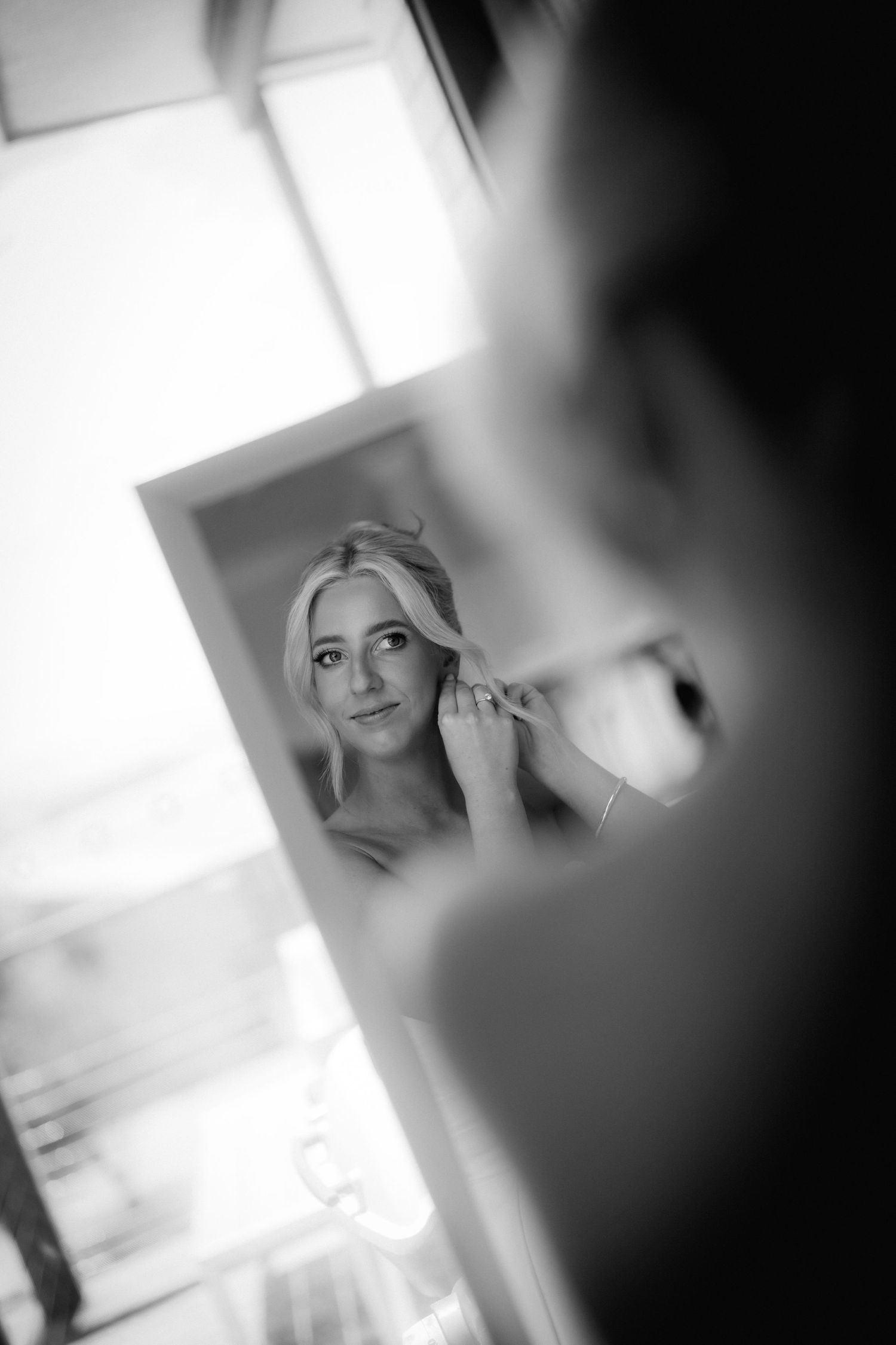 A black and white reflection in a mirror shows final touches of wedding day preparation.