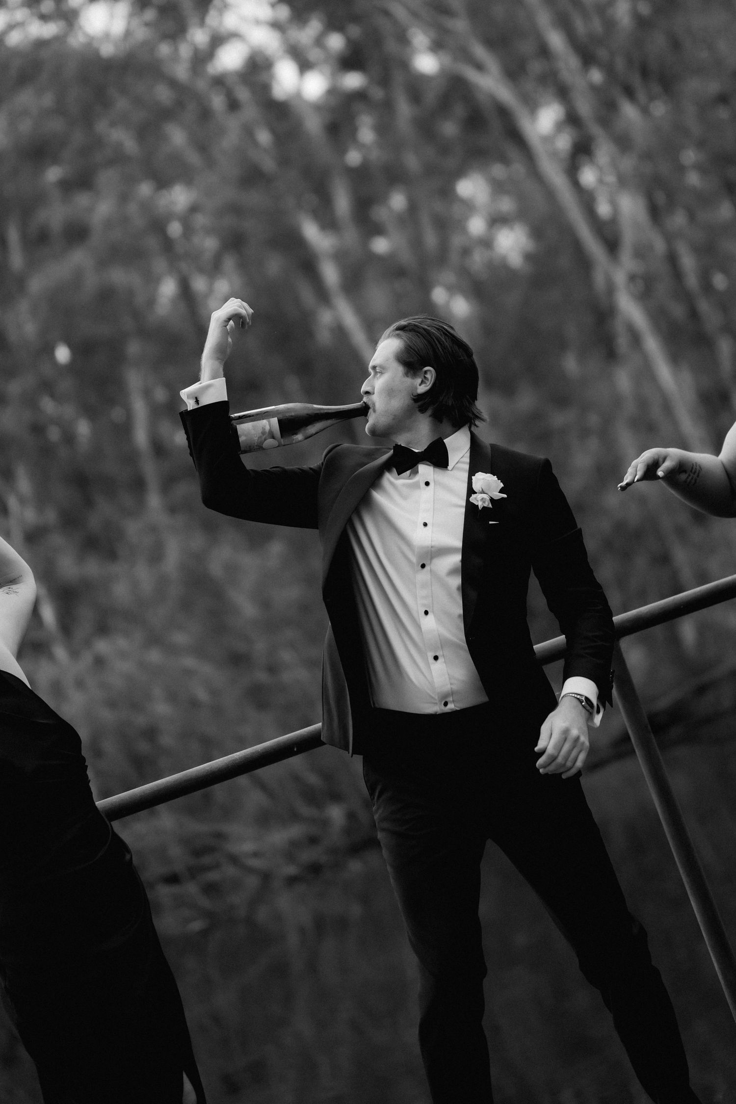 Groomsmen in tuxedos striking dramatic poses against a natural backdrop.