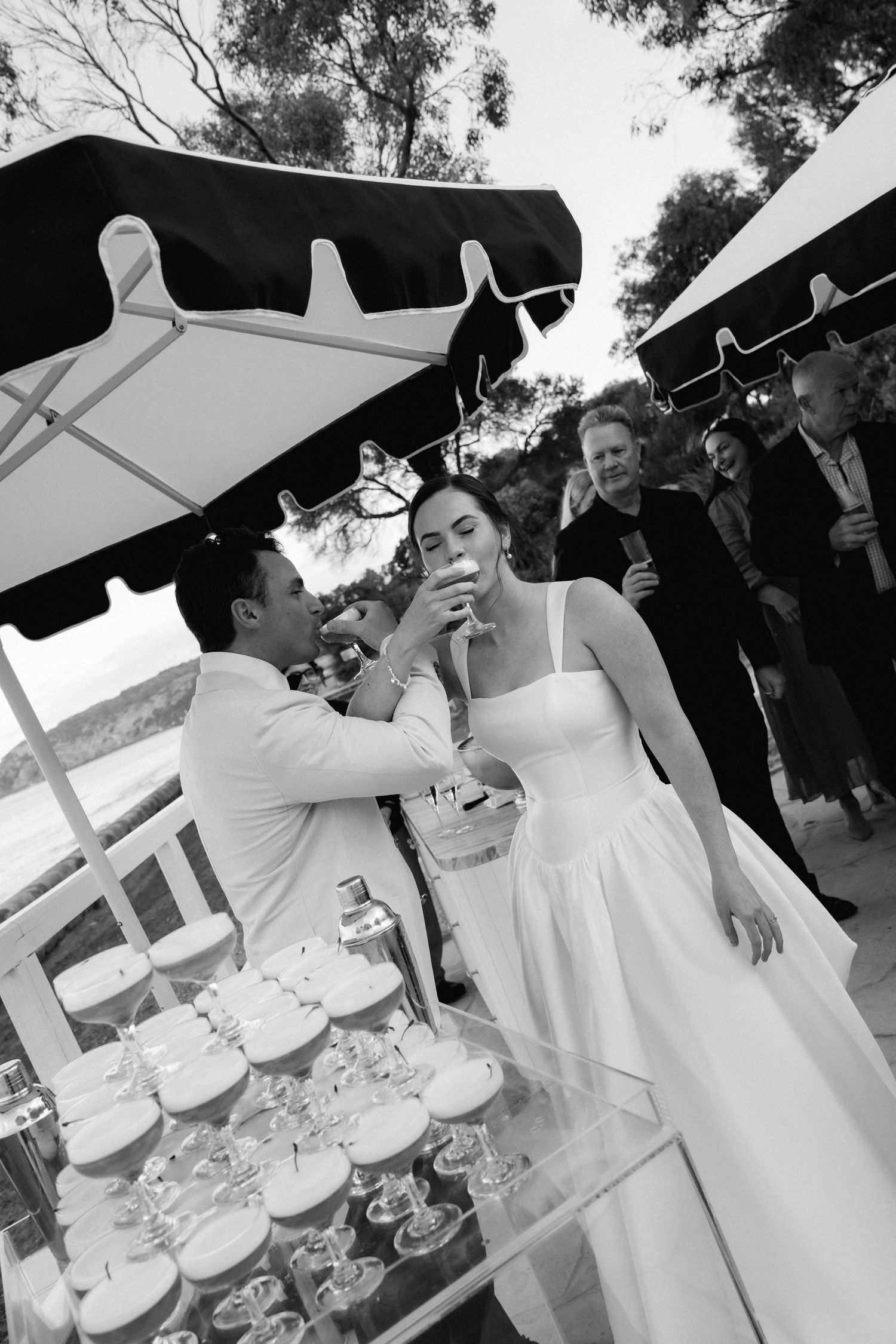 Wedding reception scene with guests gathered around a tiered white cake.