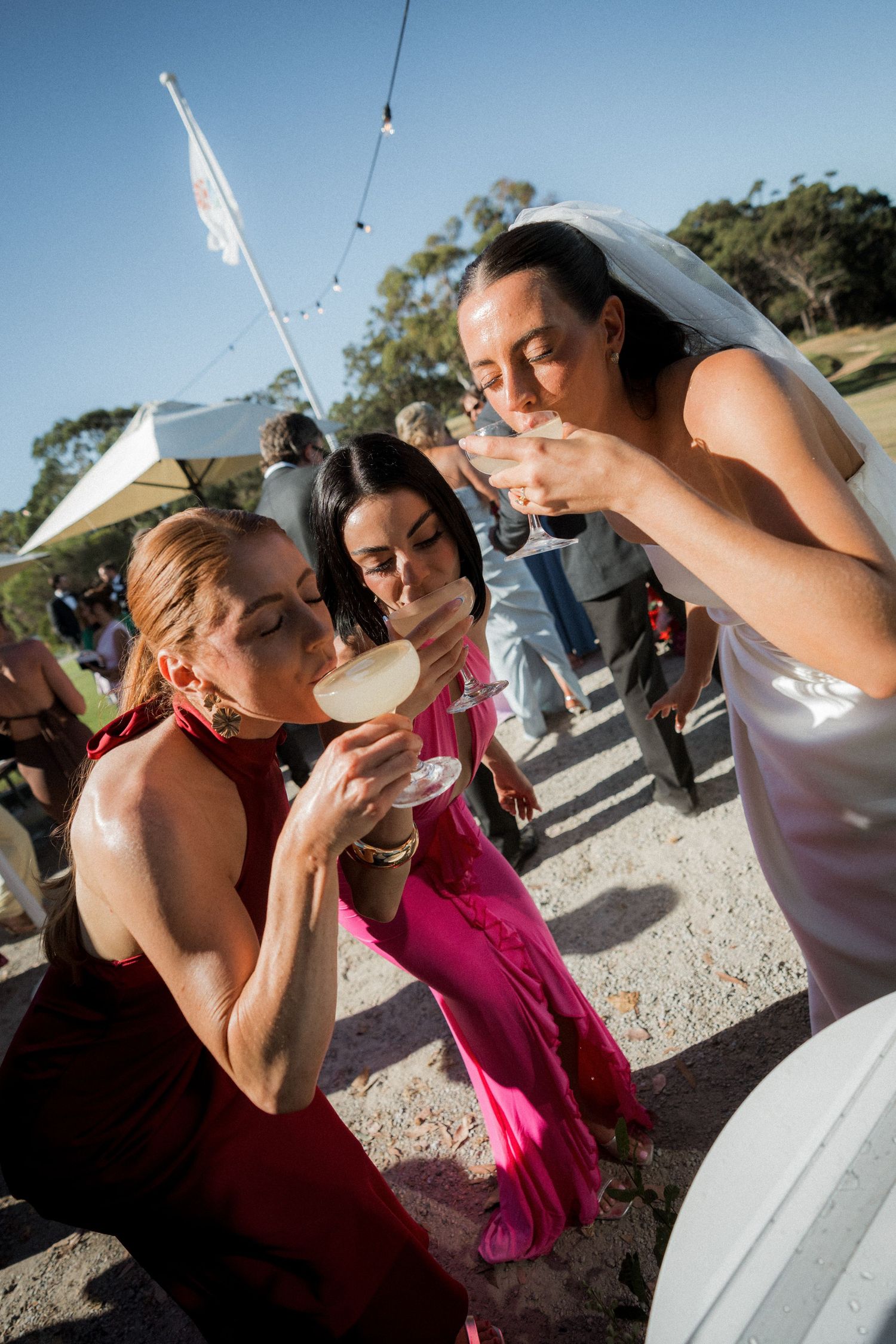 Wedding party members taking shots together at an outdoor reception.