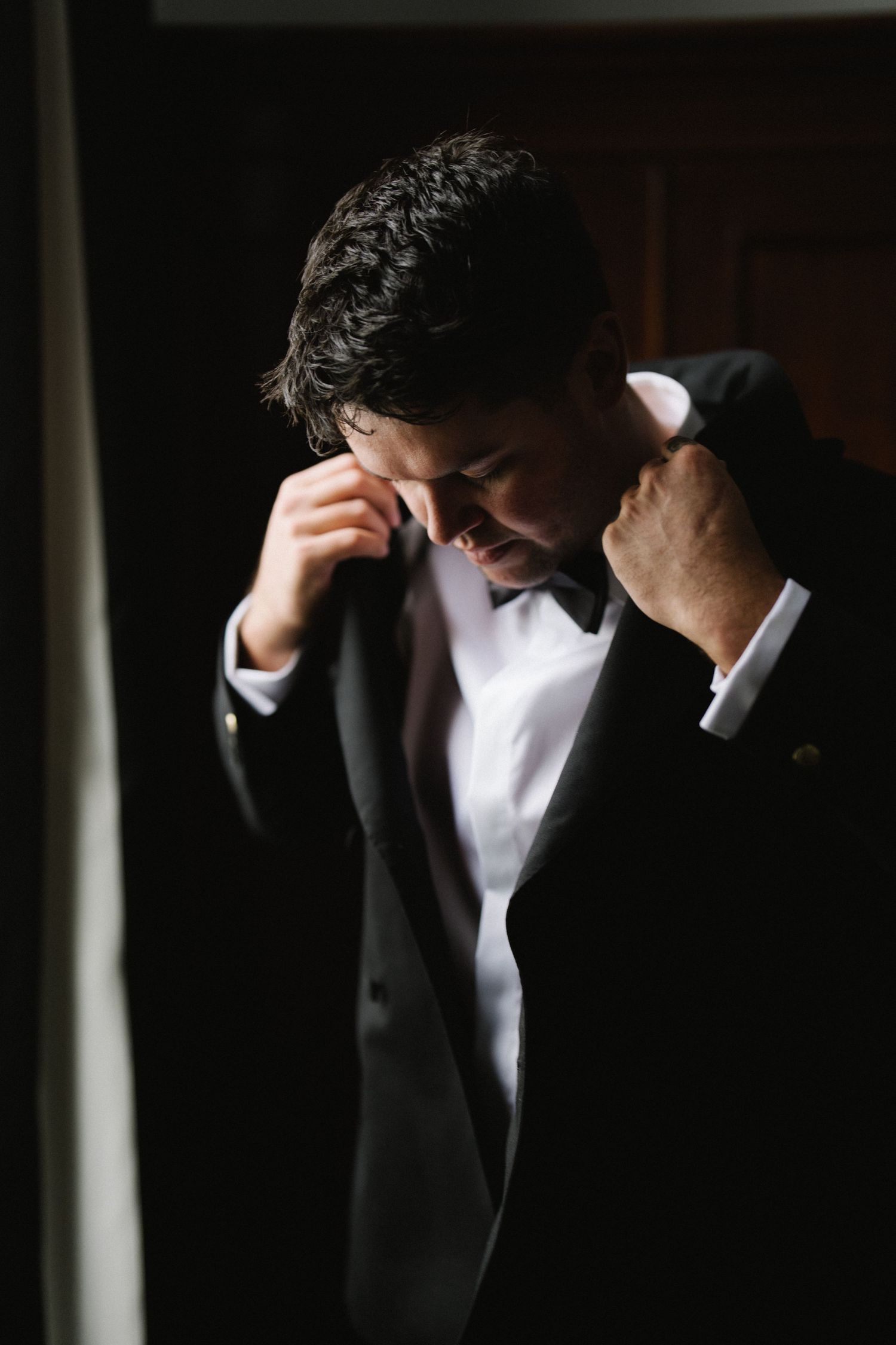 Dramatic black and white portrait showing formal attire with stark lighting and shadows.