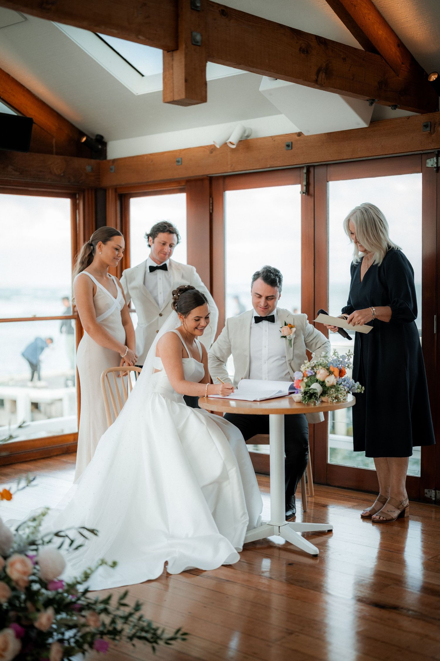Wedding preparations in a rustic wooden room with large windows and floral arrangements.