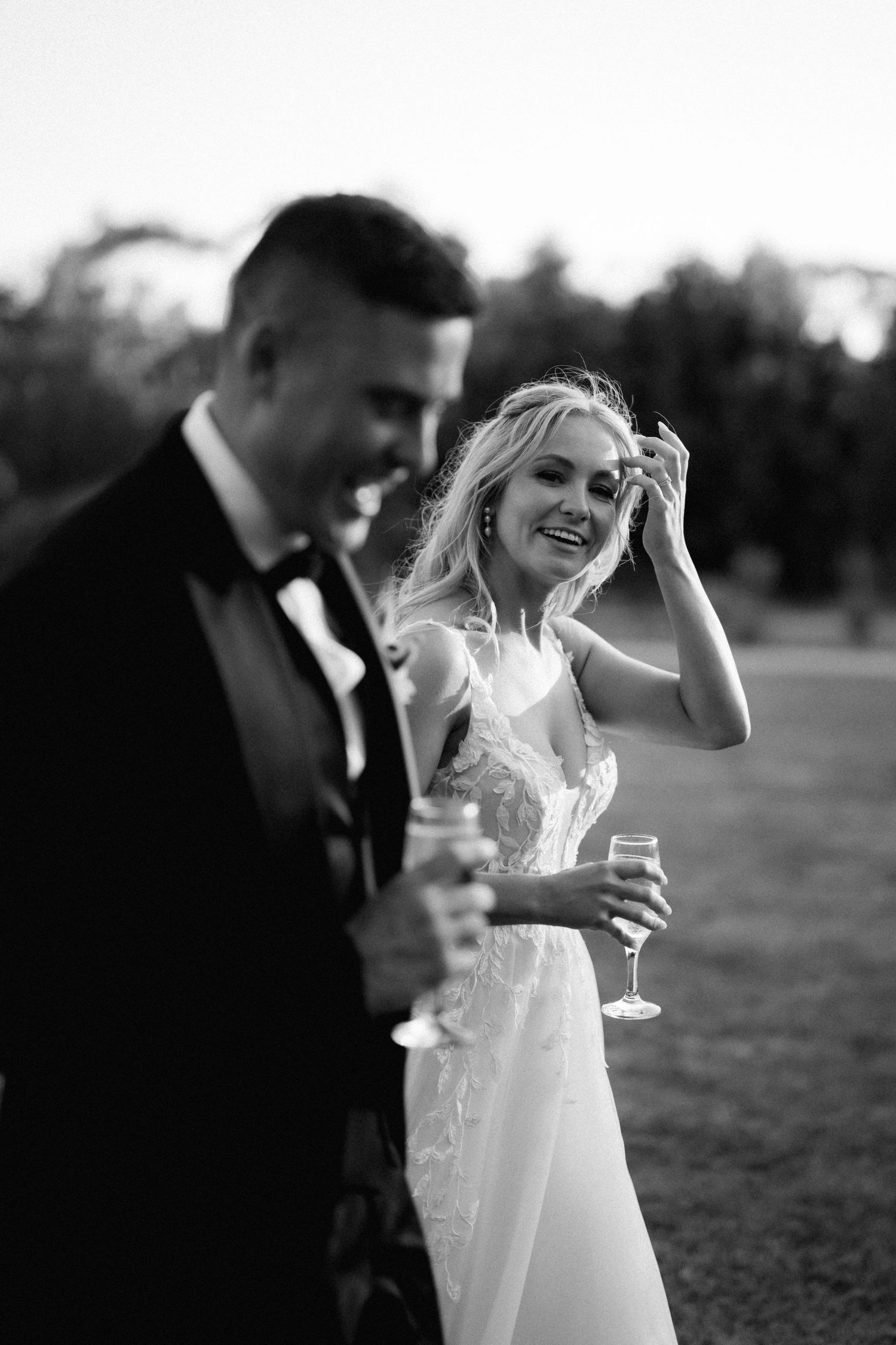 Candid moment of newlyweds laughing together during outdoor wedding reception.
