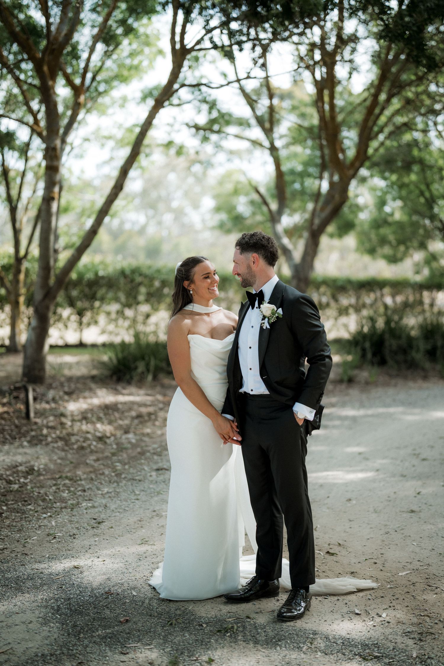 Candid wedding photos of couple in formal attire posing under trees.