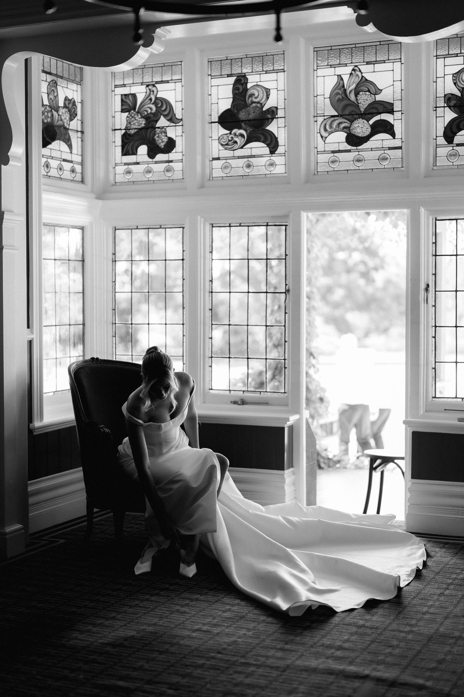 Black and white panorama of sunlit wedding venue interior with large windows.