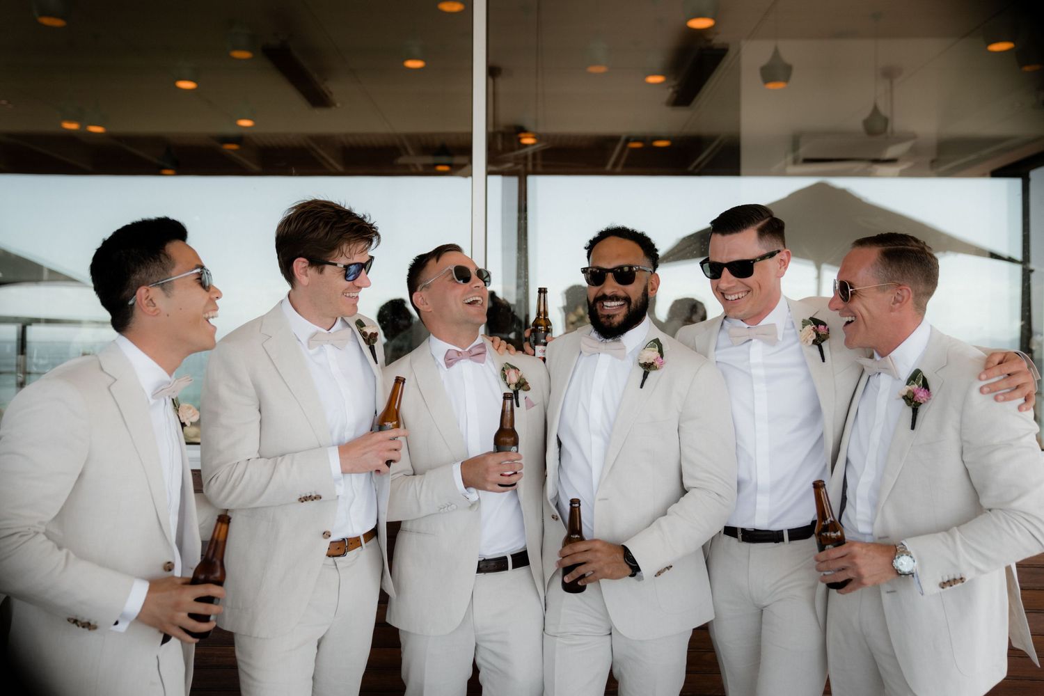 A group of groomsmen in white shirts and sunglasses gather together for pre-wedding celebrations.