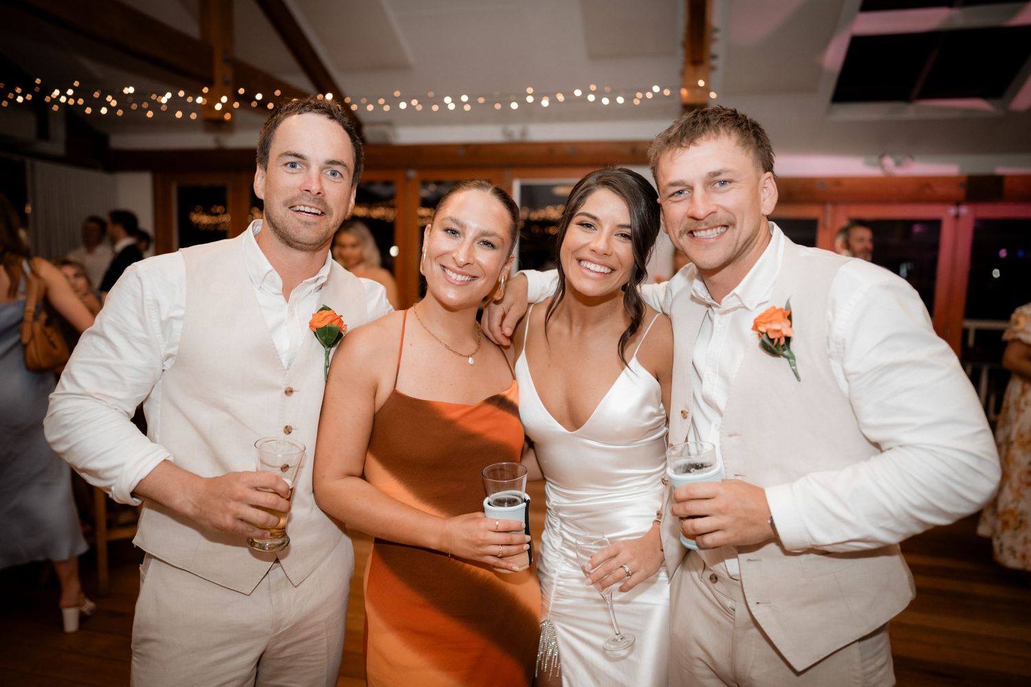 Wedding reception guests dancing and celebrating in a festively lit indoor venue.