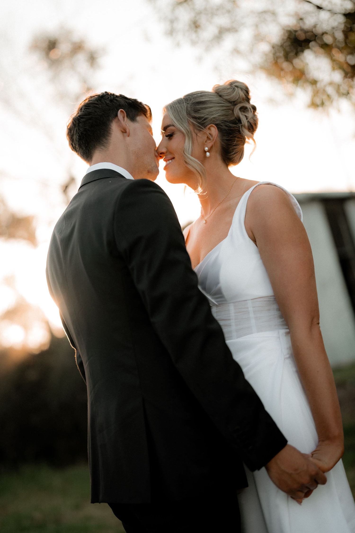A romantic sunset kiss between newlyweds with soft golden light in the background.