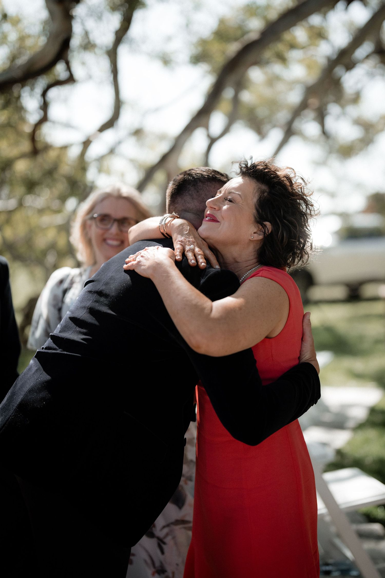 Two guests share an emotional embrace during an outdoor celebration.