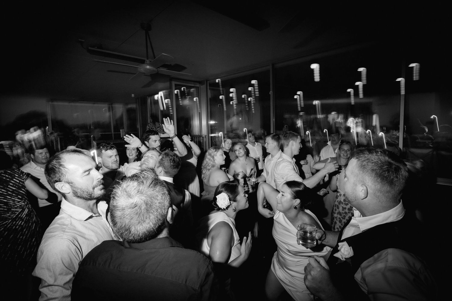 Black and white photo of wedding reception dance floor with guests celebrating.