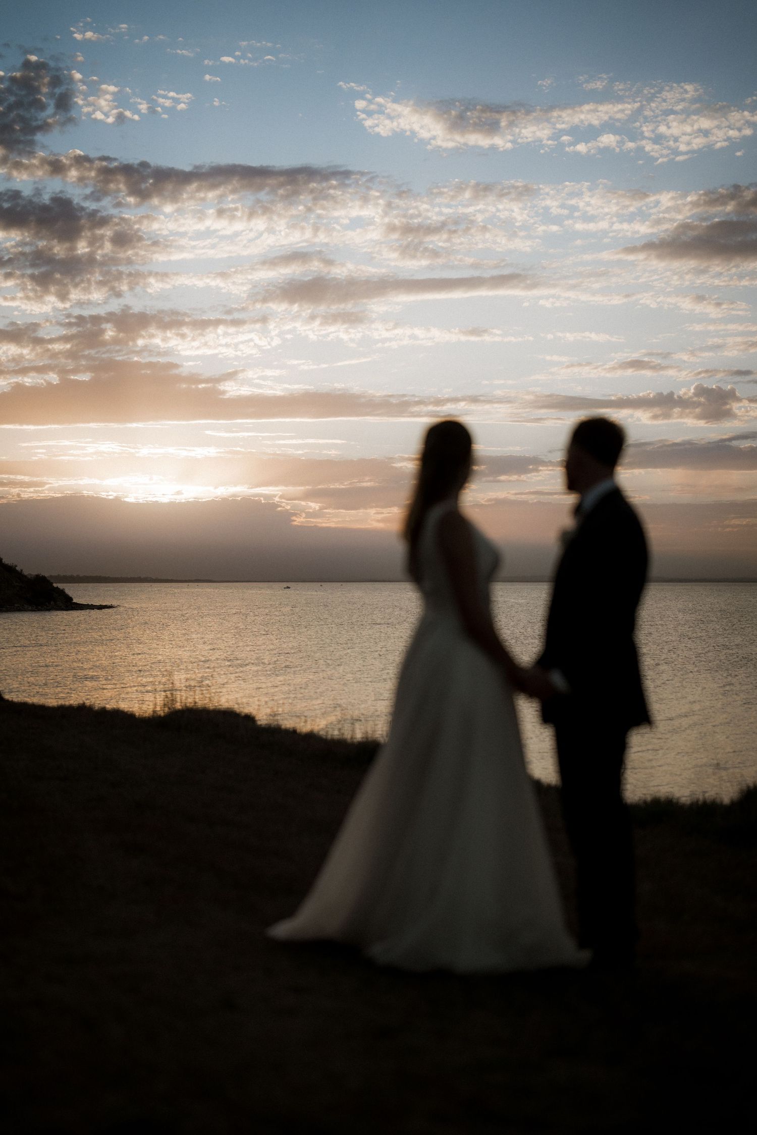 Silhouettes of a couple against a dramatic sunset sky over the ocean.