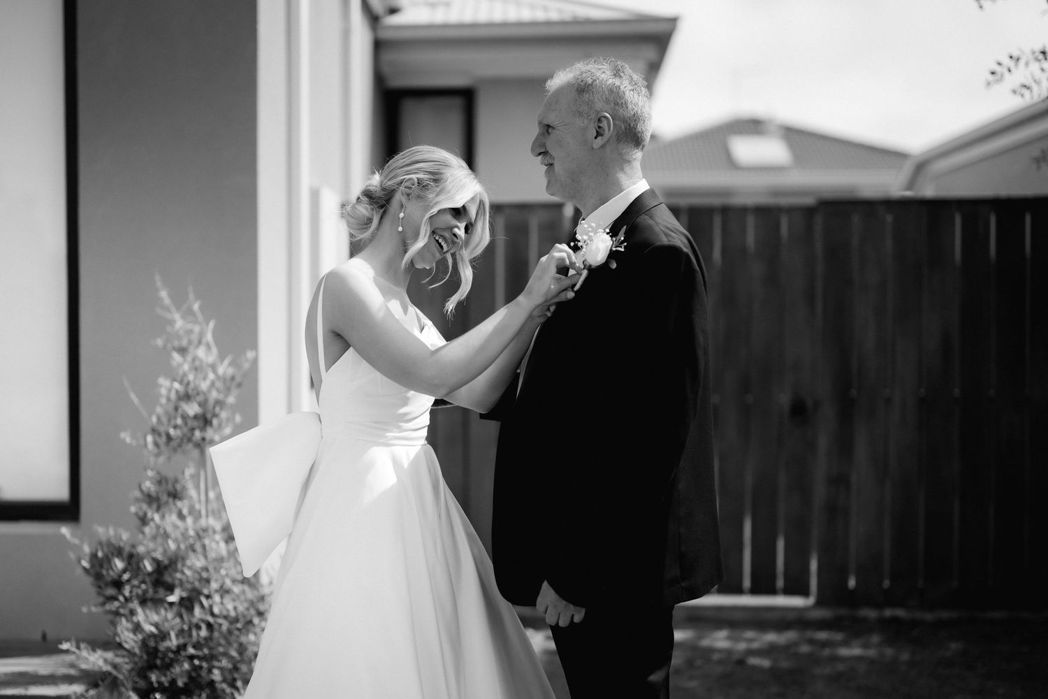 A black and white wedding photo of a tender moment between newlyweds during their first look outdoors.
