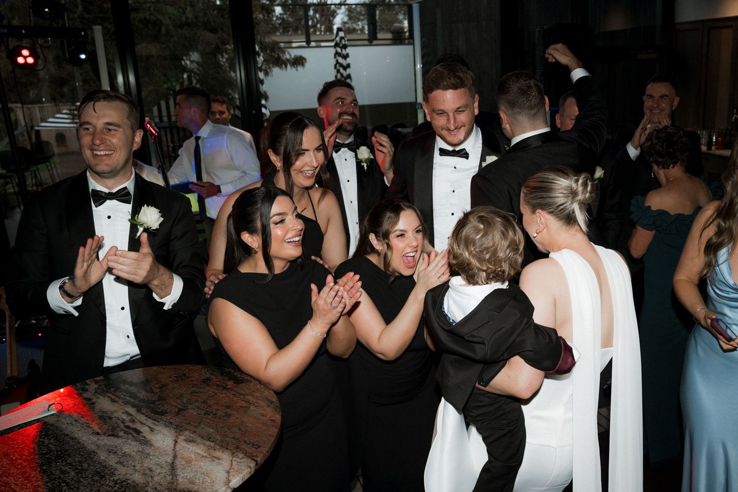 Wedding reception dance floor filled with guests in formal attire enjoying the celebration.