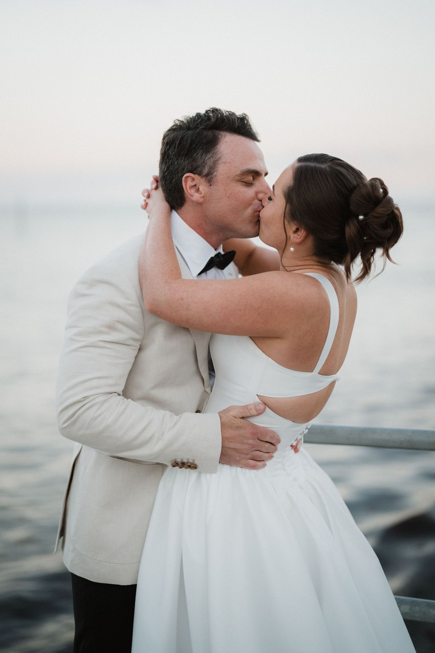 Romantic seaside wedding portrait with couple in white and cream formal attire.