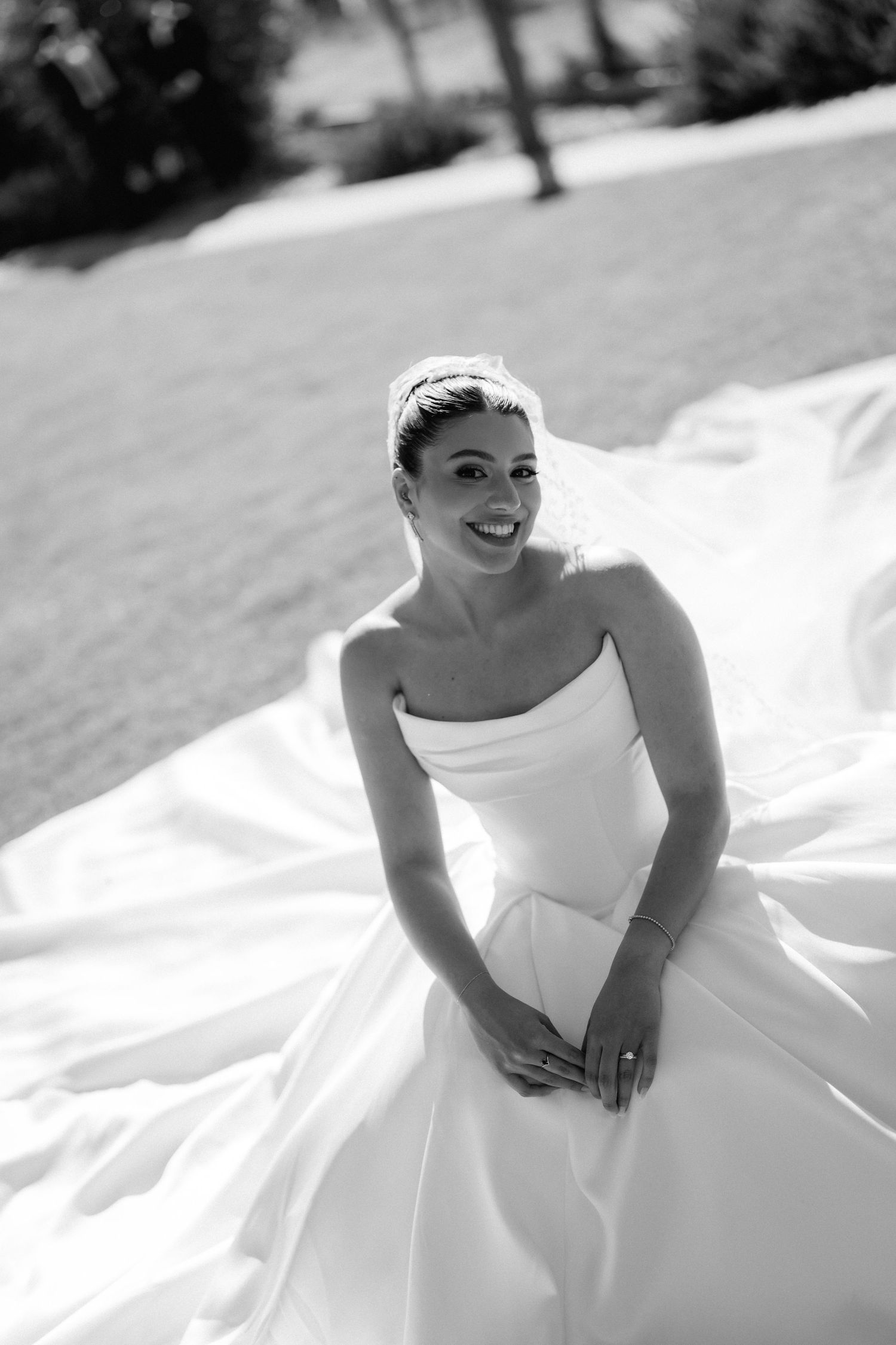 A bride in a flowing white wedding dress twirls joyfully outdoors in a series of black and white photos.