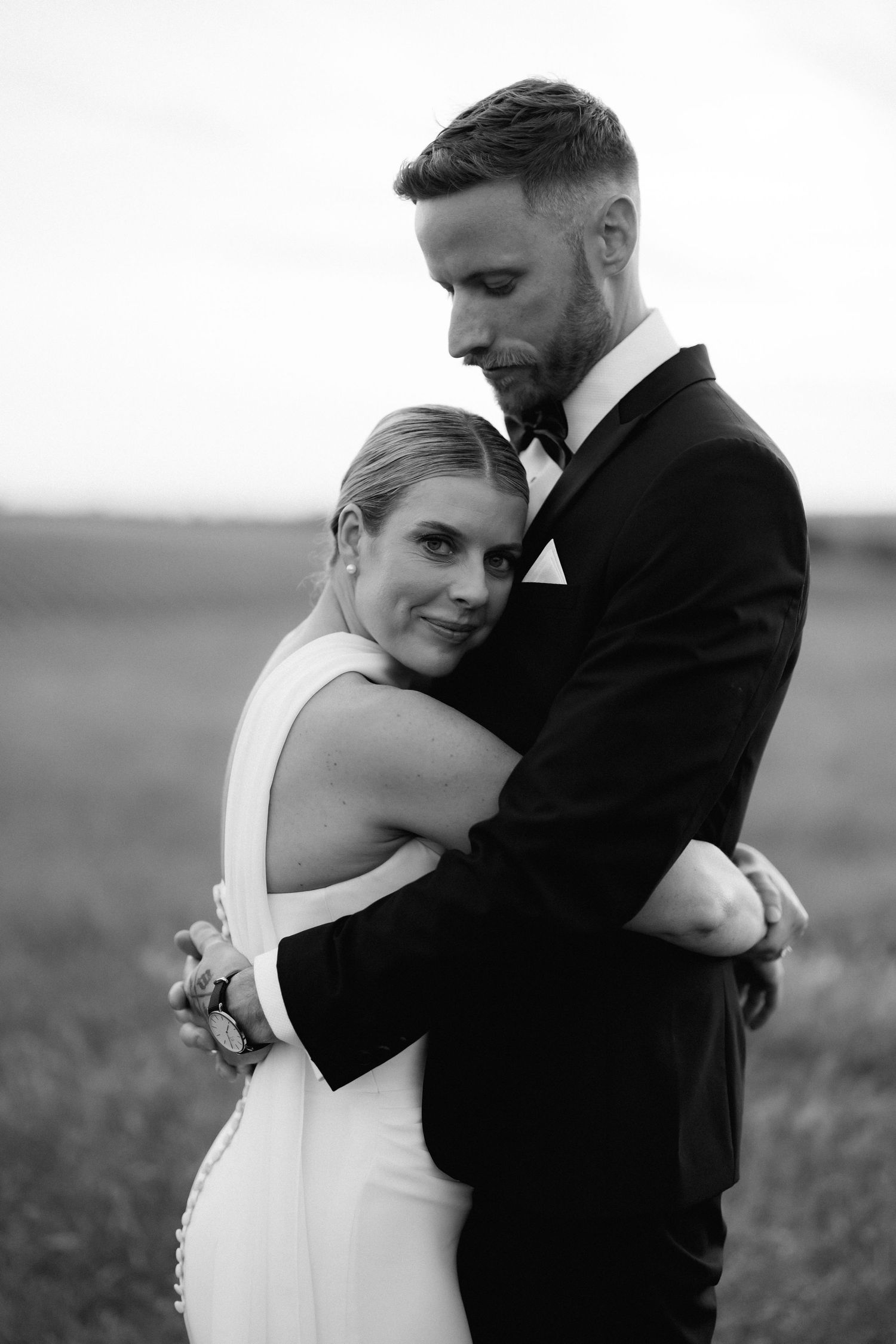 Intimate black and white wedding portraits show tender moments between newlyweds in an outdoor setting.
