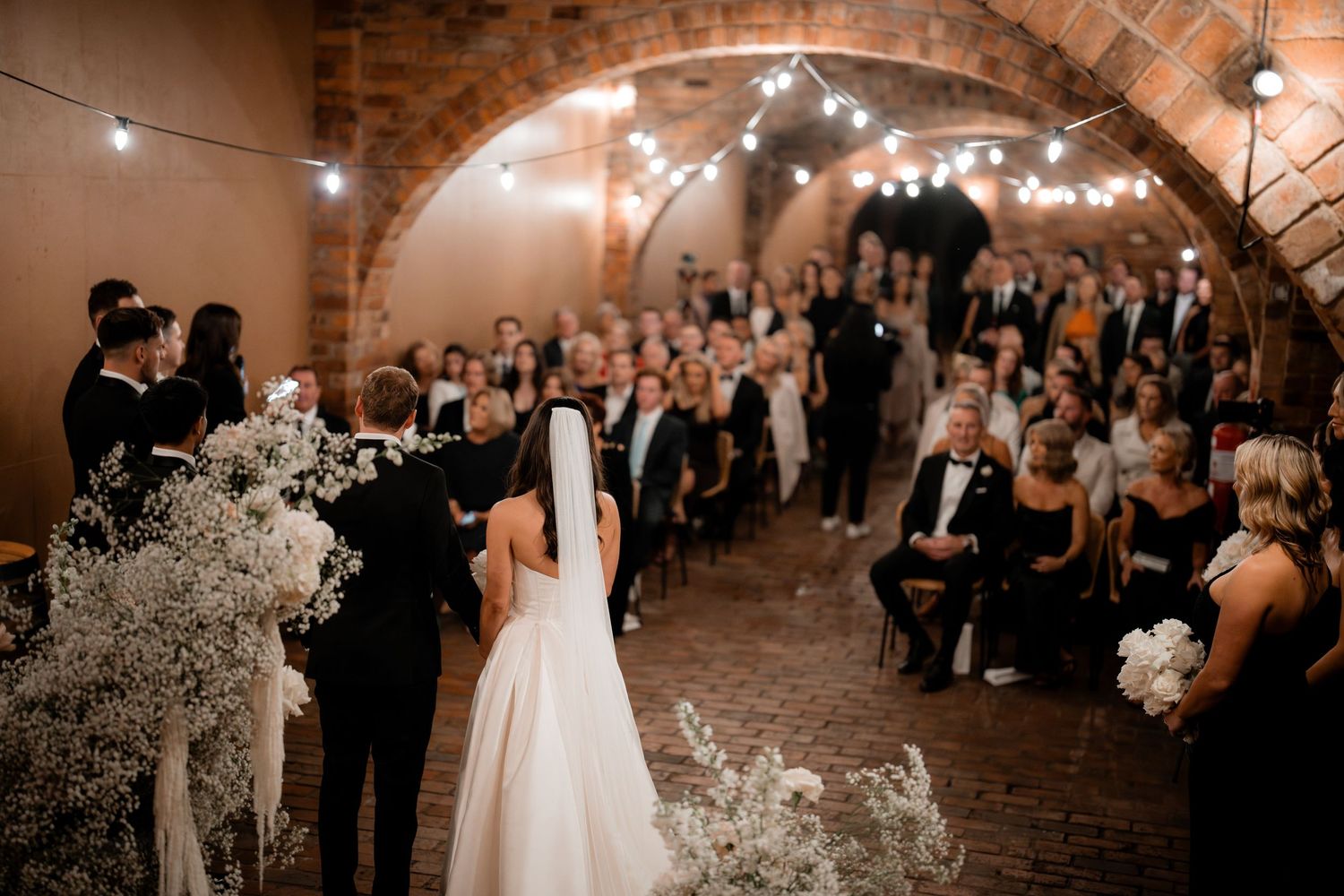 A wedding ceremony in a romantic brick archway venue with baby's breath floral decorations.