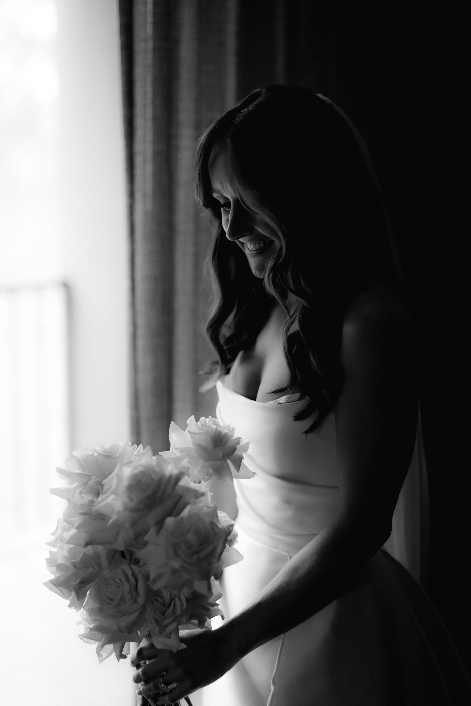 Artistic black and white portrait with white rose bouquet and wedding gown.