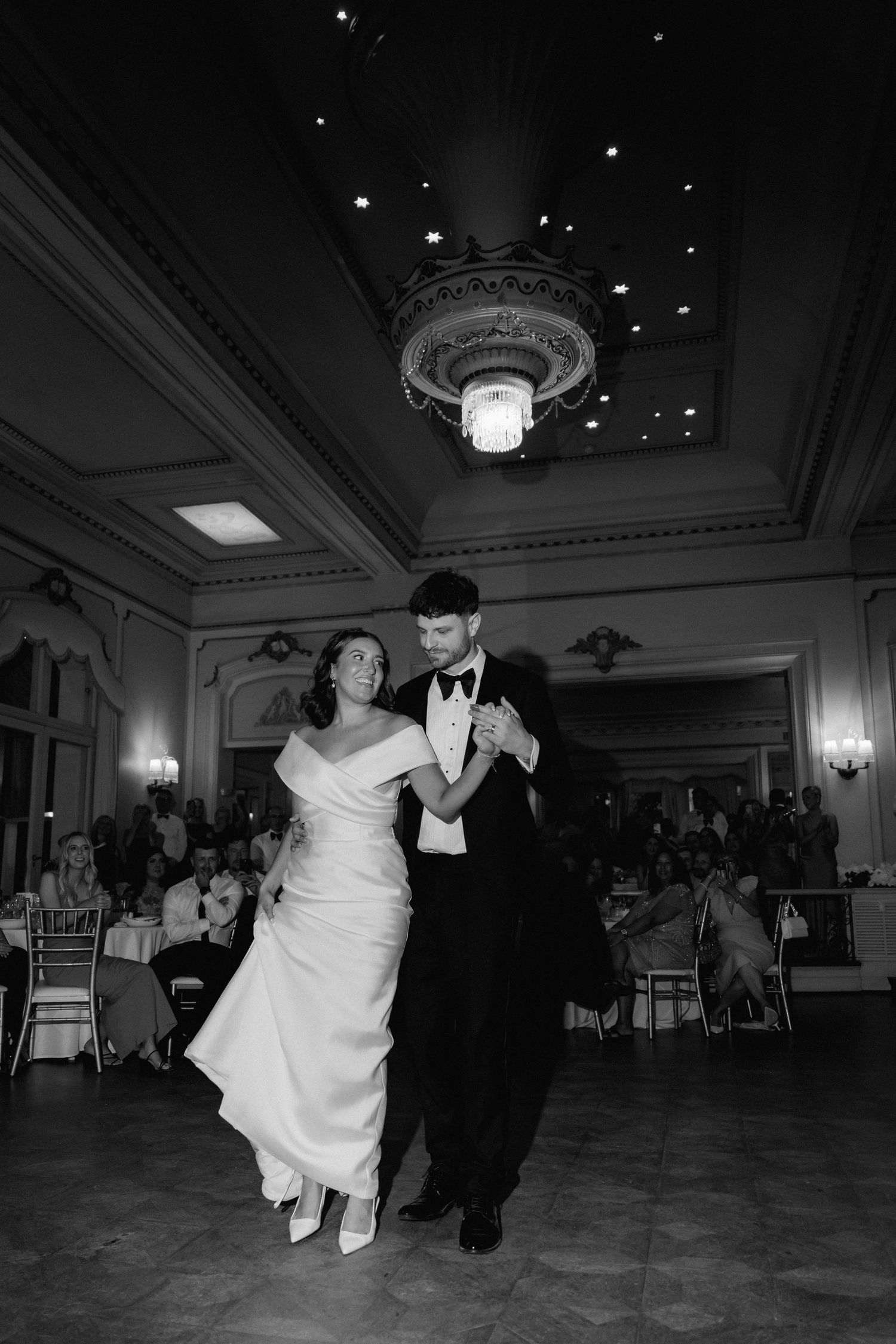 A dancing couple performs an energetic dance move in a grand ballroom during a formal celebration event.