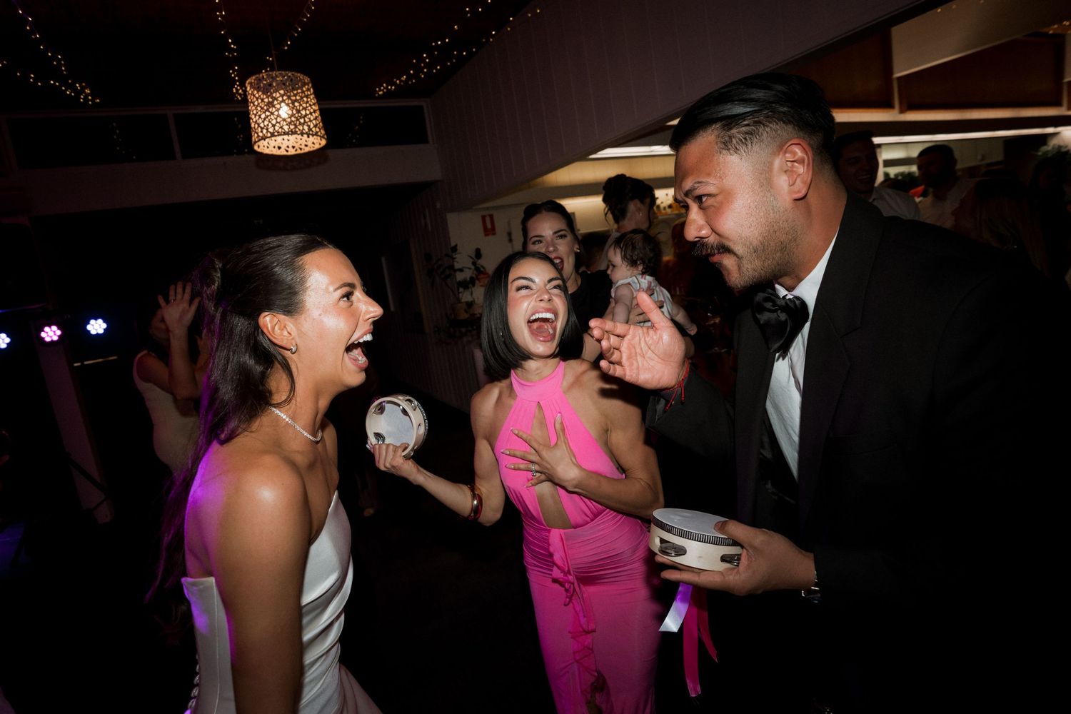 Wedding guests celebrate on the dance floor during evening reception.