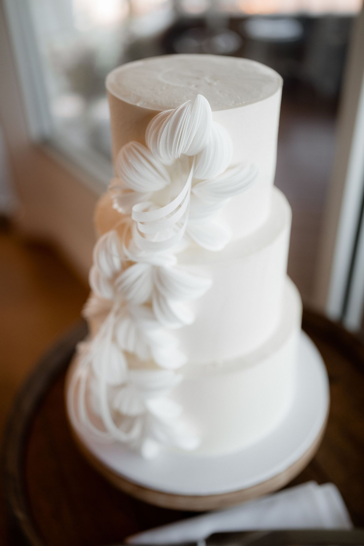 Elegant white wedding cake with delicate ruffled details photographed from multiple angles.