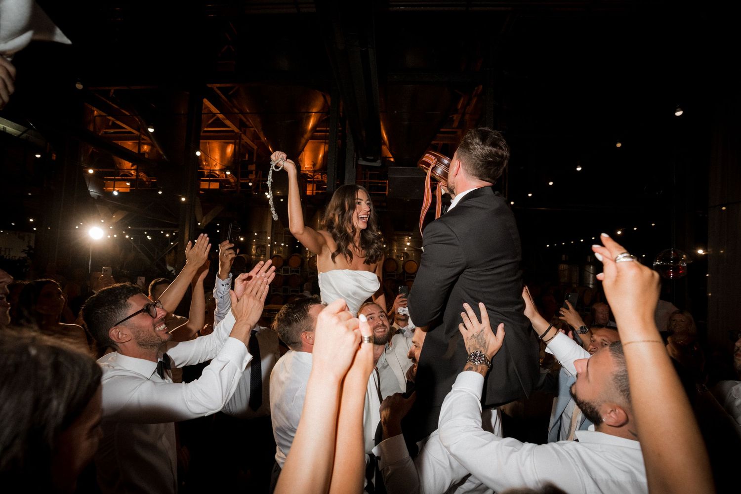 Crowd of people dancing and having fun at a dimly lit nighttime celebration event.