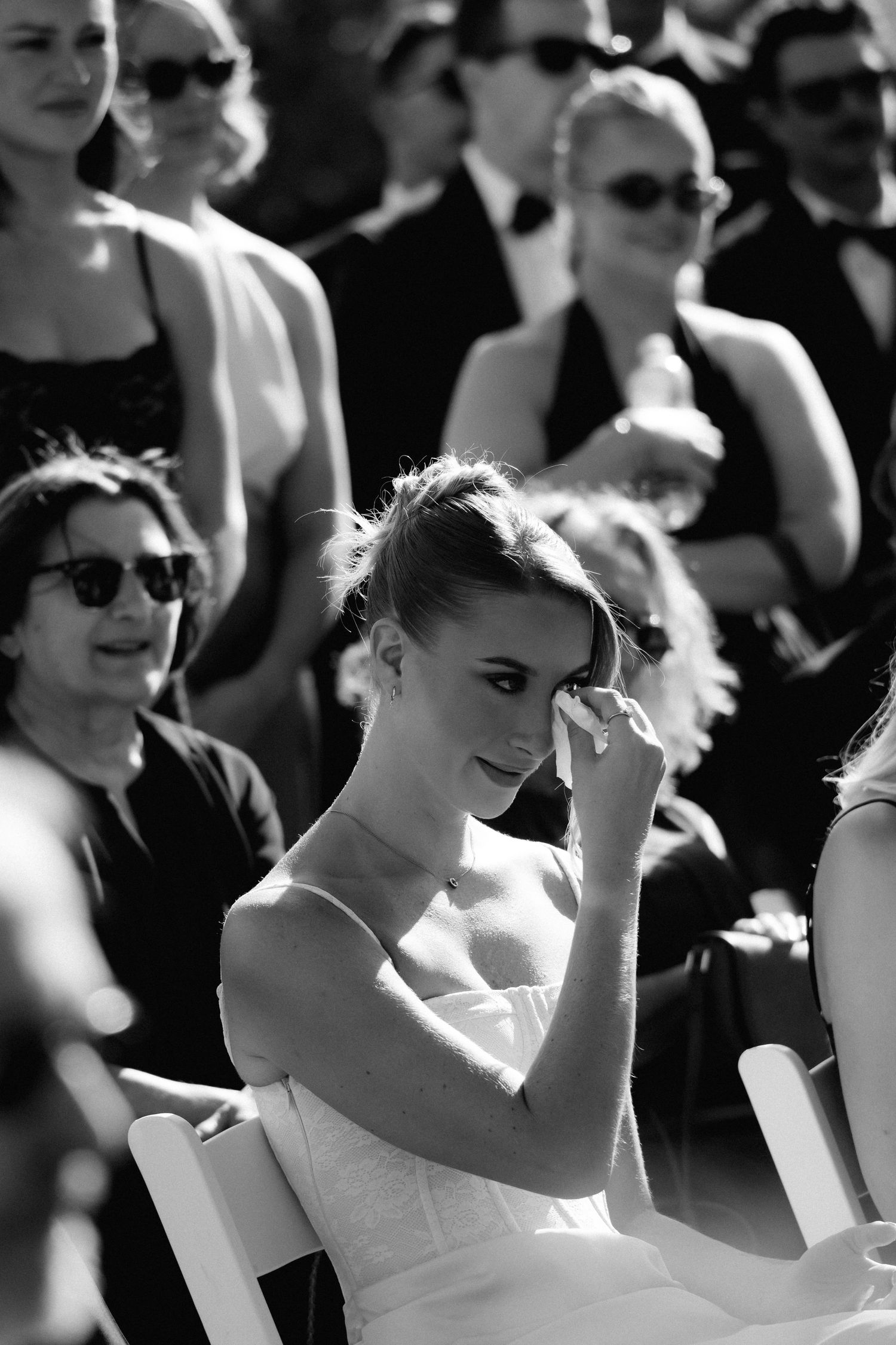 Black and white photo of wedding guests dancing with hands in the air at an outdoor celebration.
