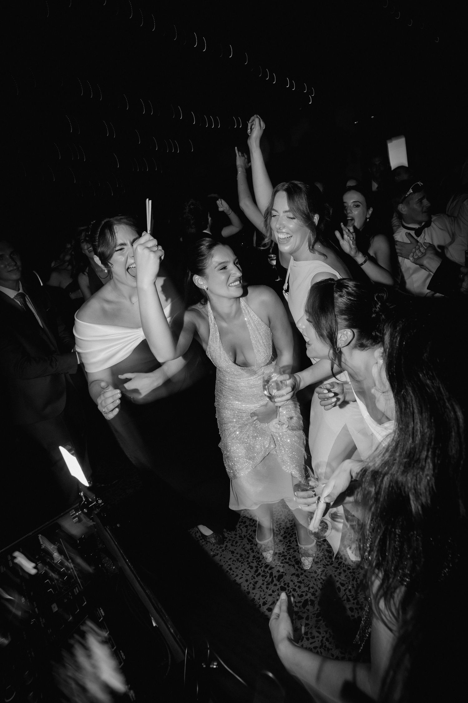 Black and white photo of a lively dance party with people dancing energetically in a dark room.