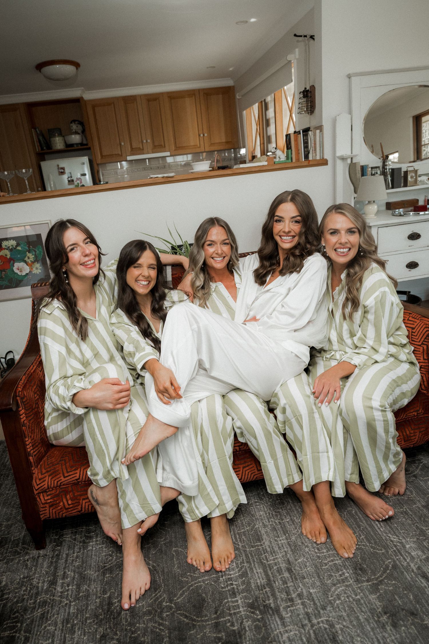 A group in matching striped robes and white loungewear poses together on a gray carpet in a home setting.