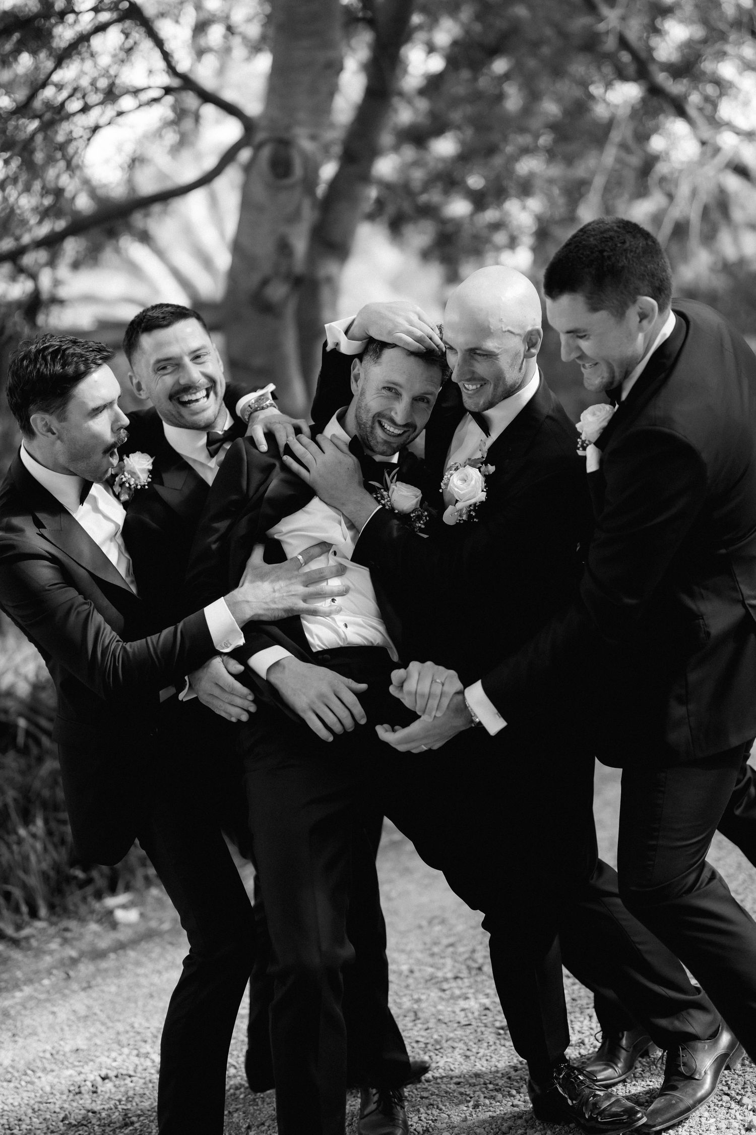 Black and white photos of groomsmen laughing and celebrating together outdoors.