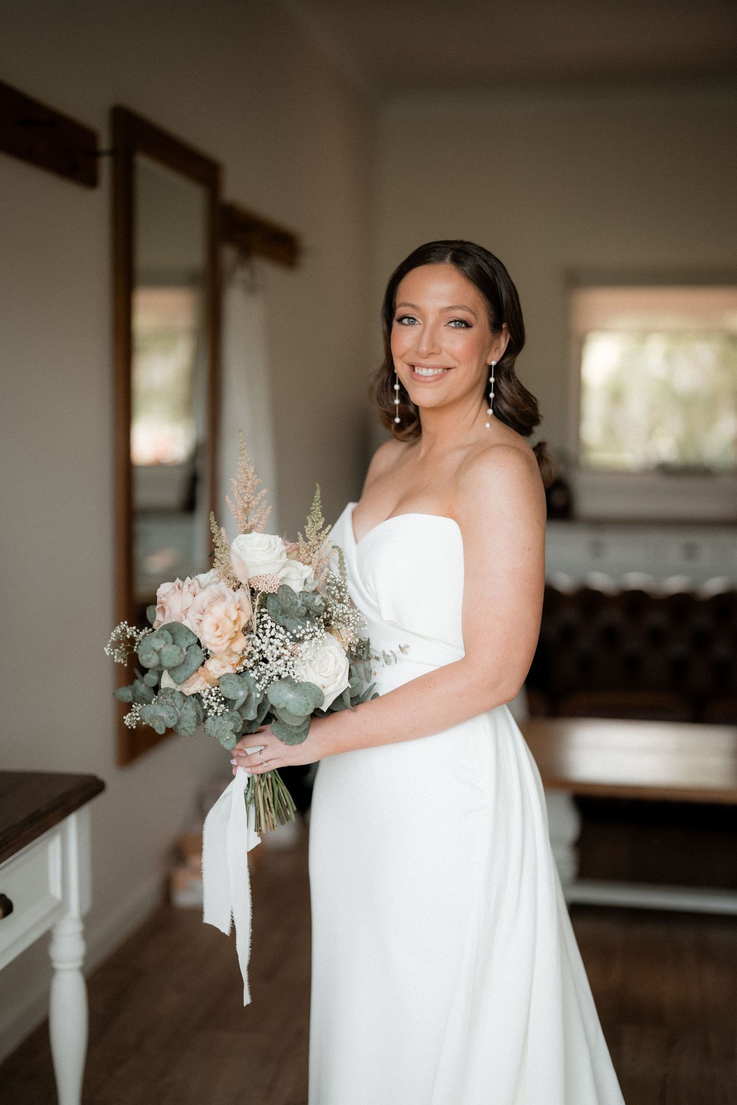 Beautiful bridal portrait showing an elegant white wedding gown and pastel bouquet in natural light.