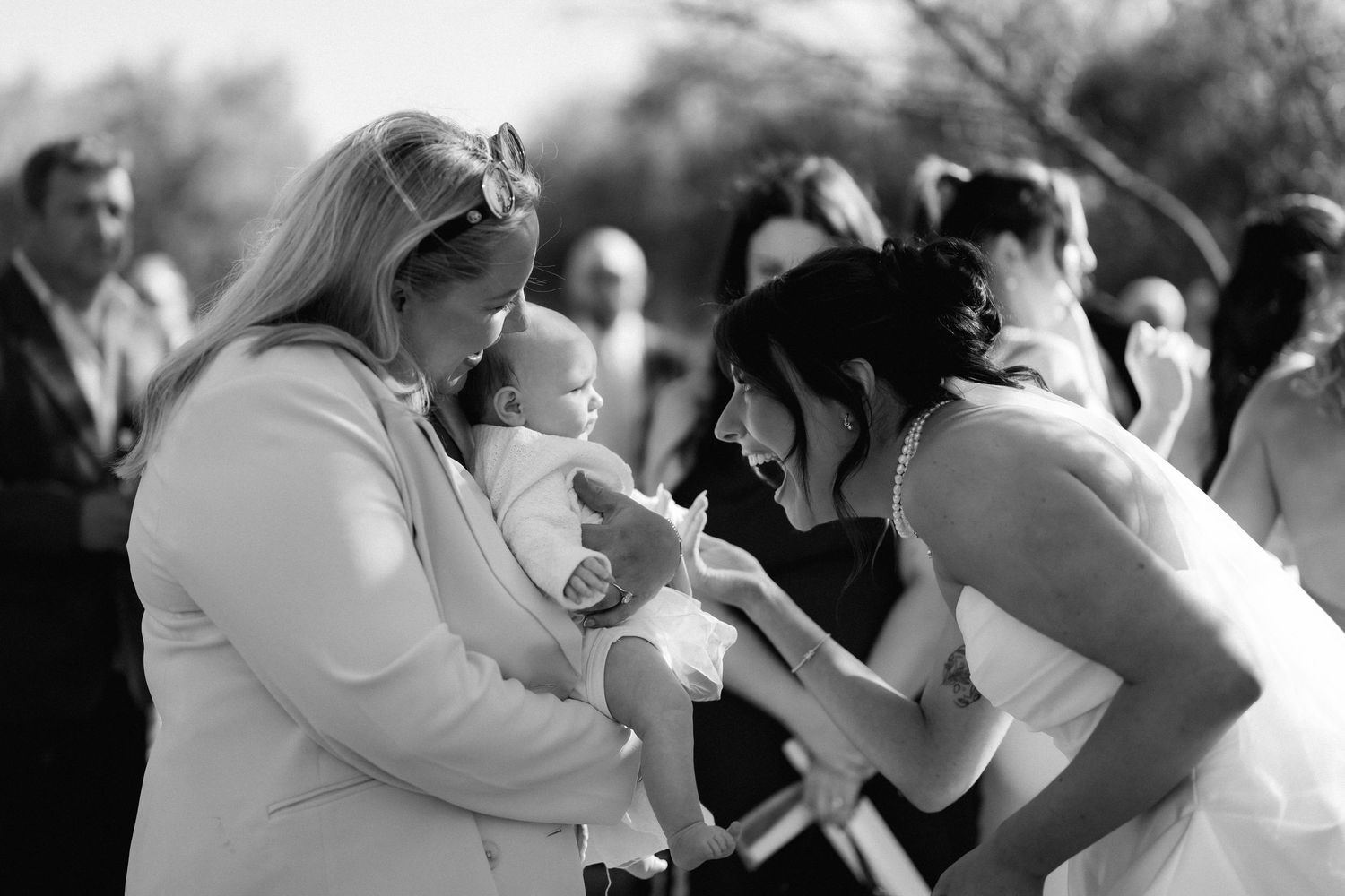 Wedding guests embrace and share emotional moments during an outdoor celebration.