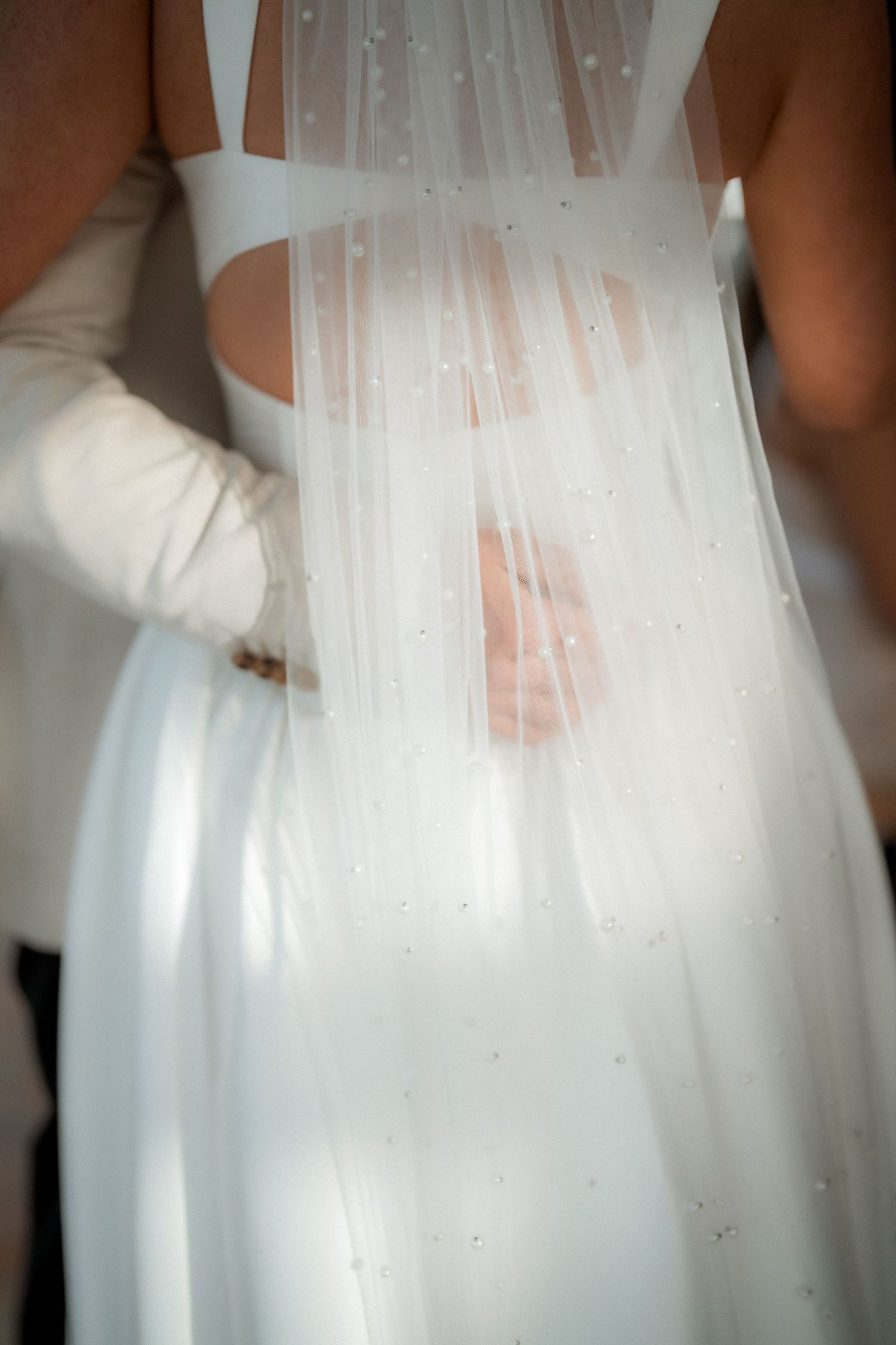 Close-up detail of a white wedding dress with delicate tulle fabric and intricate details.