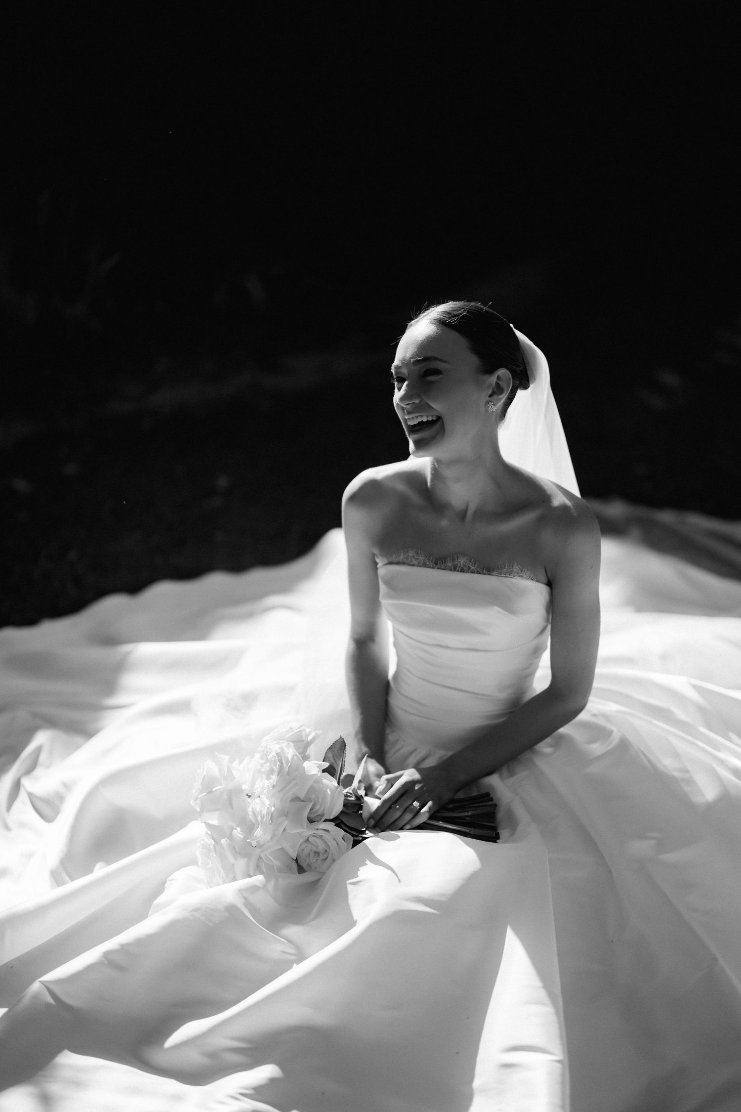 A black and white artistic portrait showcasing the details of a bride's wedding gown.