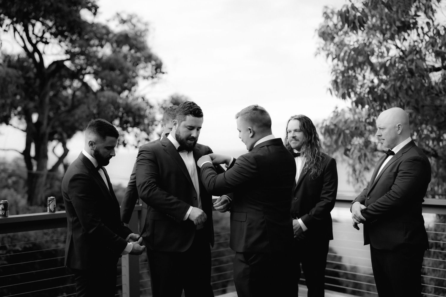 Black and white photograph of people gathered outdoors for a formal occasion with trees in the background.