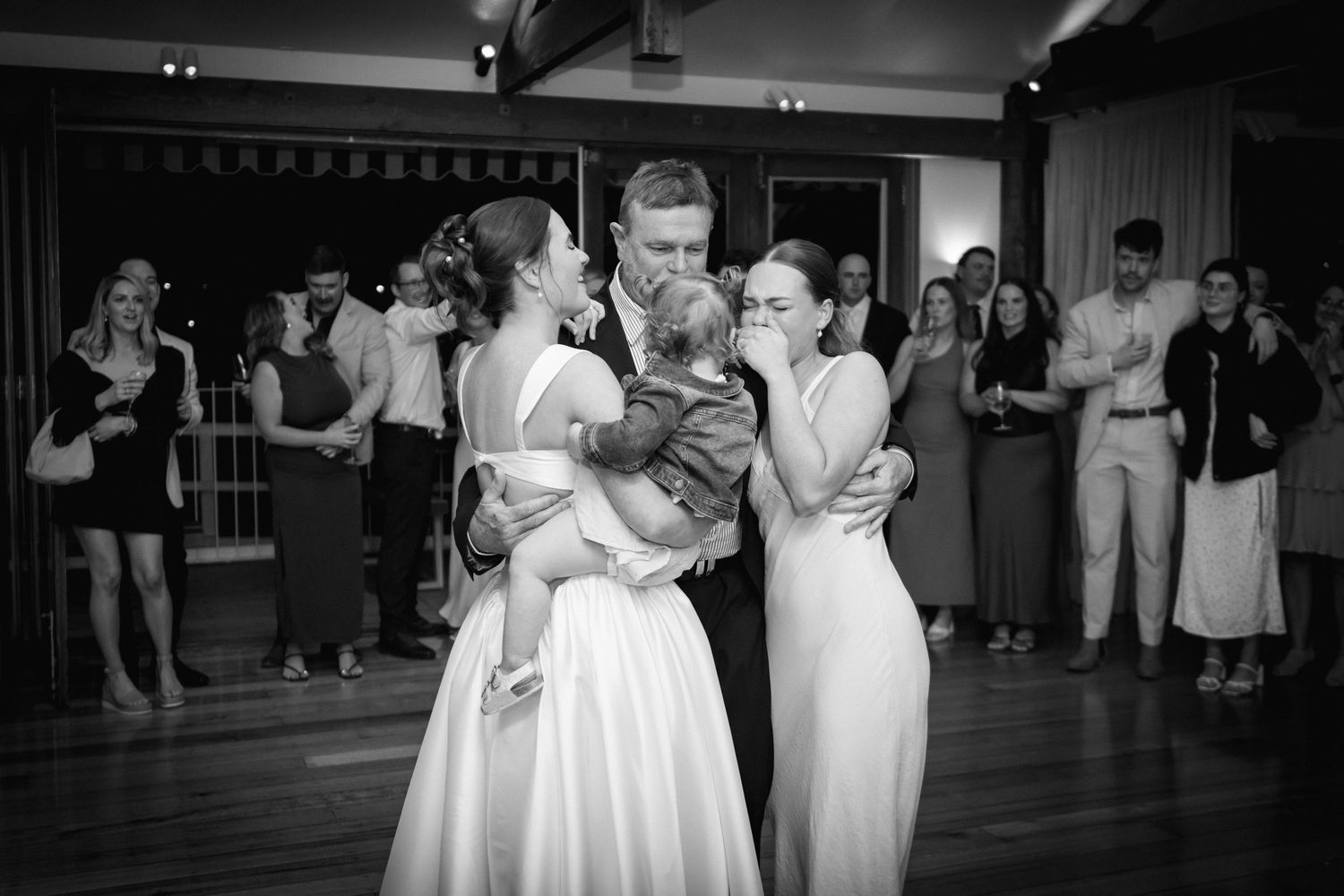 Wedding party dances together during a reception celebration in black and white photography.