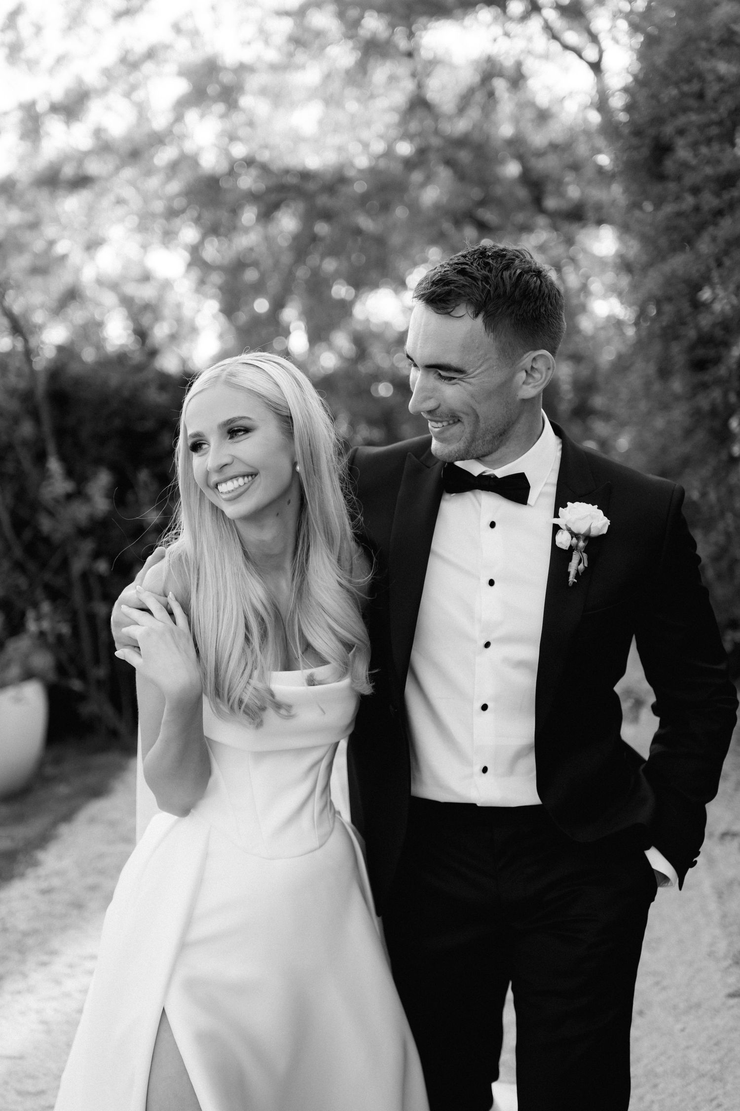 Black and white wedding photo series showing candid romantic moments between newlyweds in an outdoor garden setting.