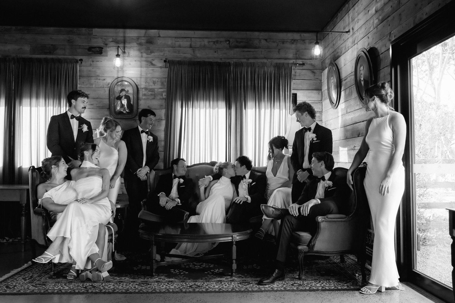 Black and white photo of wedding ceremony in rustic indoor venue with wooden beams.