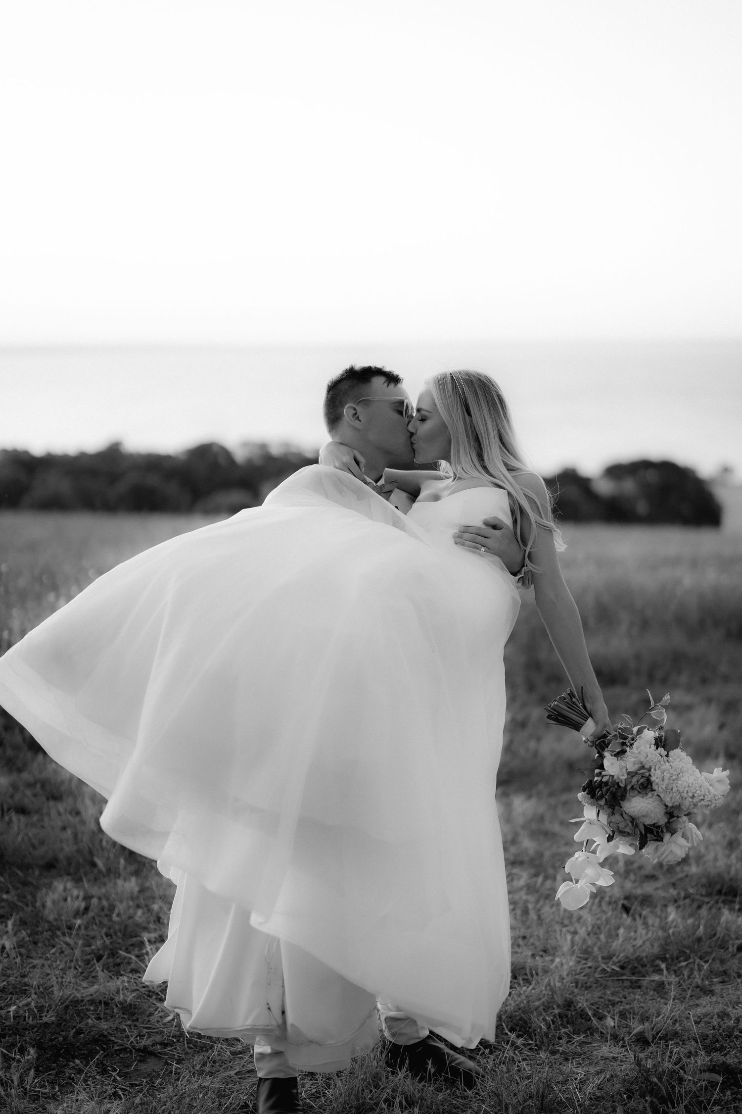 An intimate black and white wedding portrait in a natural field setting.