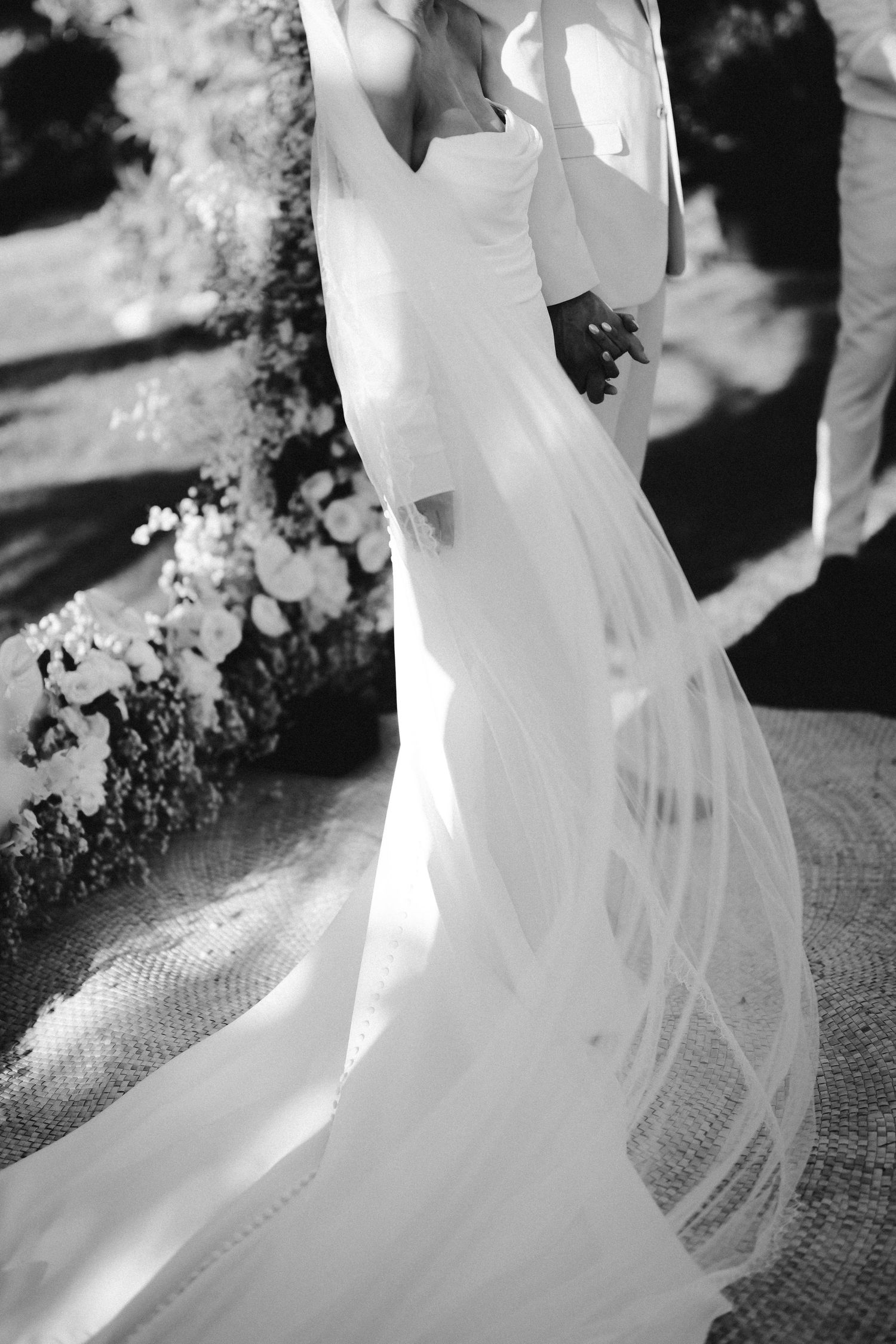 Elegant white wedding dress with flowing train captured in artistic black and white photography.