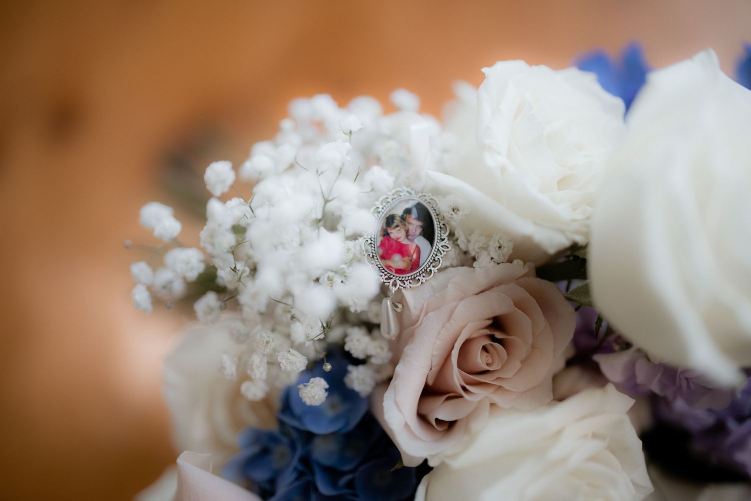 A delicate floral arrangement features pale pink roses with baby's breath and hints of blue flowers.