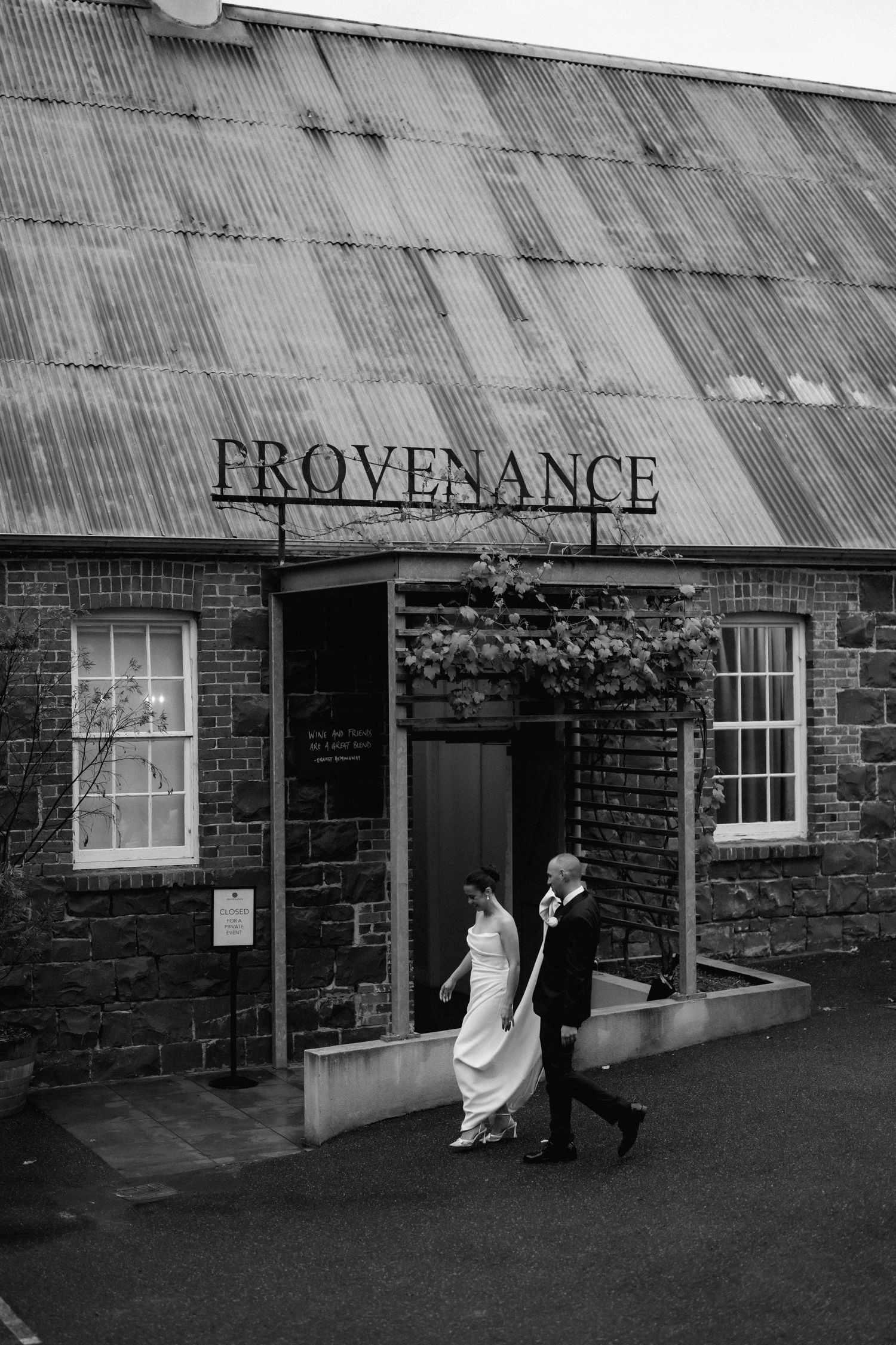 Wedding couple enters historic stone building with Provenance signage in dramatic black and white.
