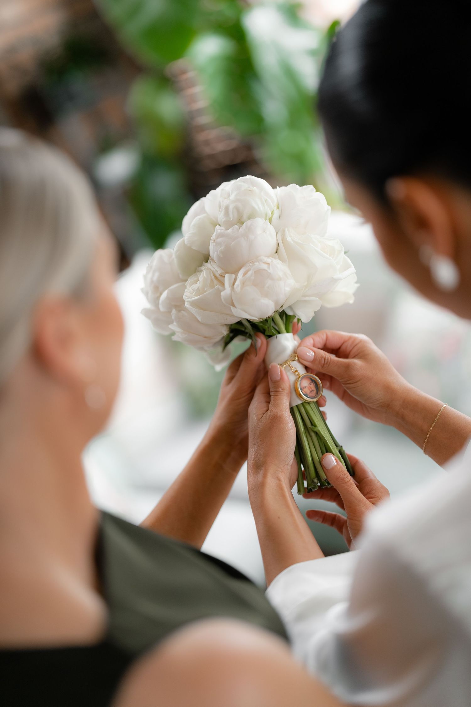 Hands delicately adjusting a beautiful bouquet of white peonies tied with ribbon.