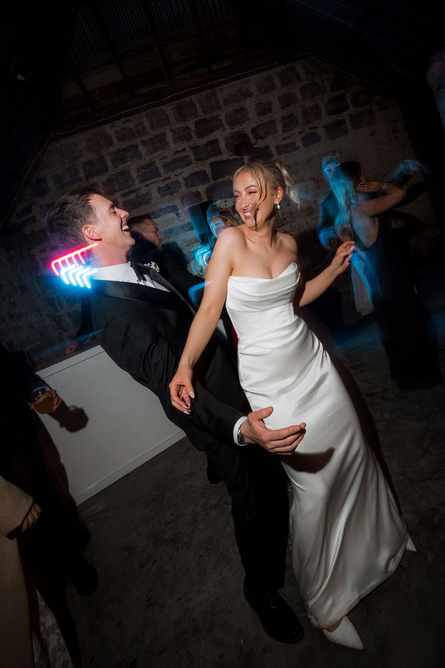 Wedding reception dance floor scene with dramatic lighting and dancing couples.