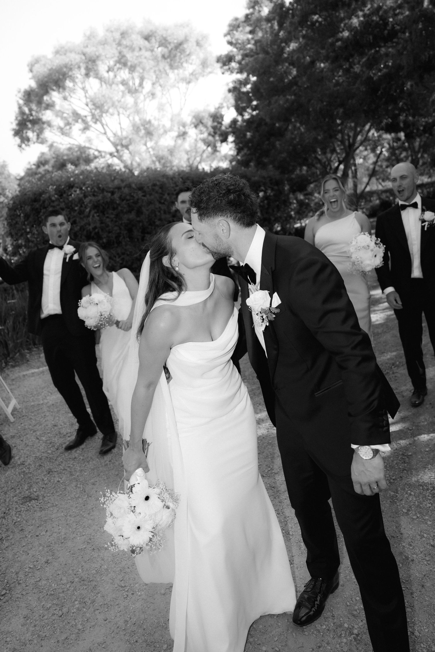 Black and white photo of a romantic moment at an outdoor wedding celebration.