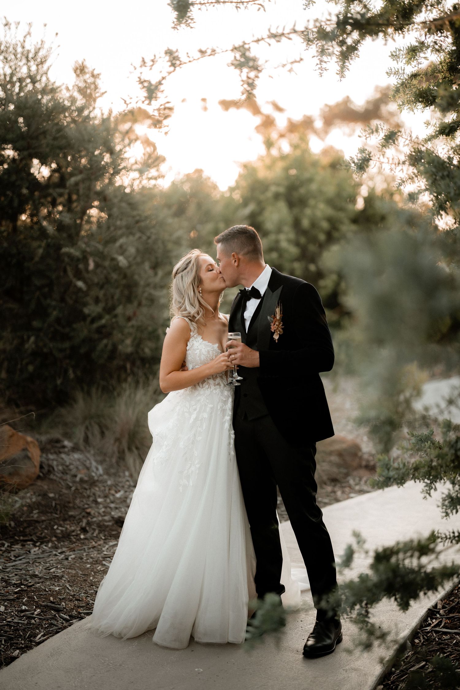 Couple sharing an intimate moment during their outdoor wedding photoshoot at sunset in a natural setting.