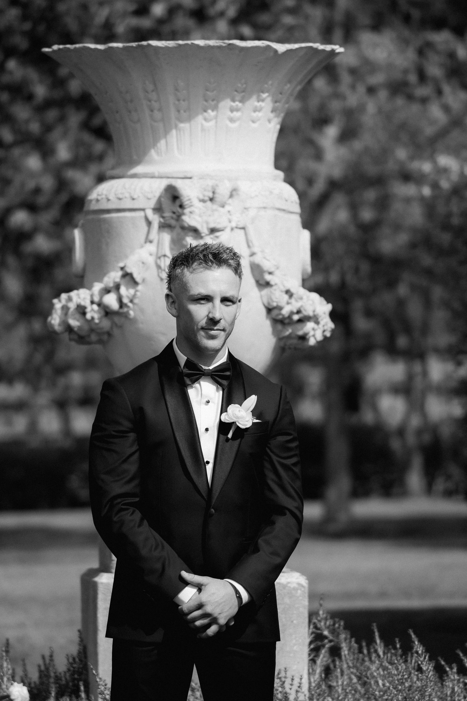 Classic formal portrait in front of an ornate white garden urn with decorative details.